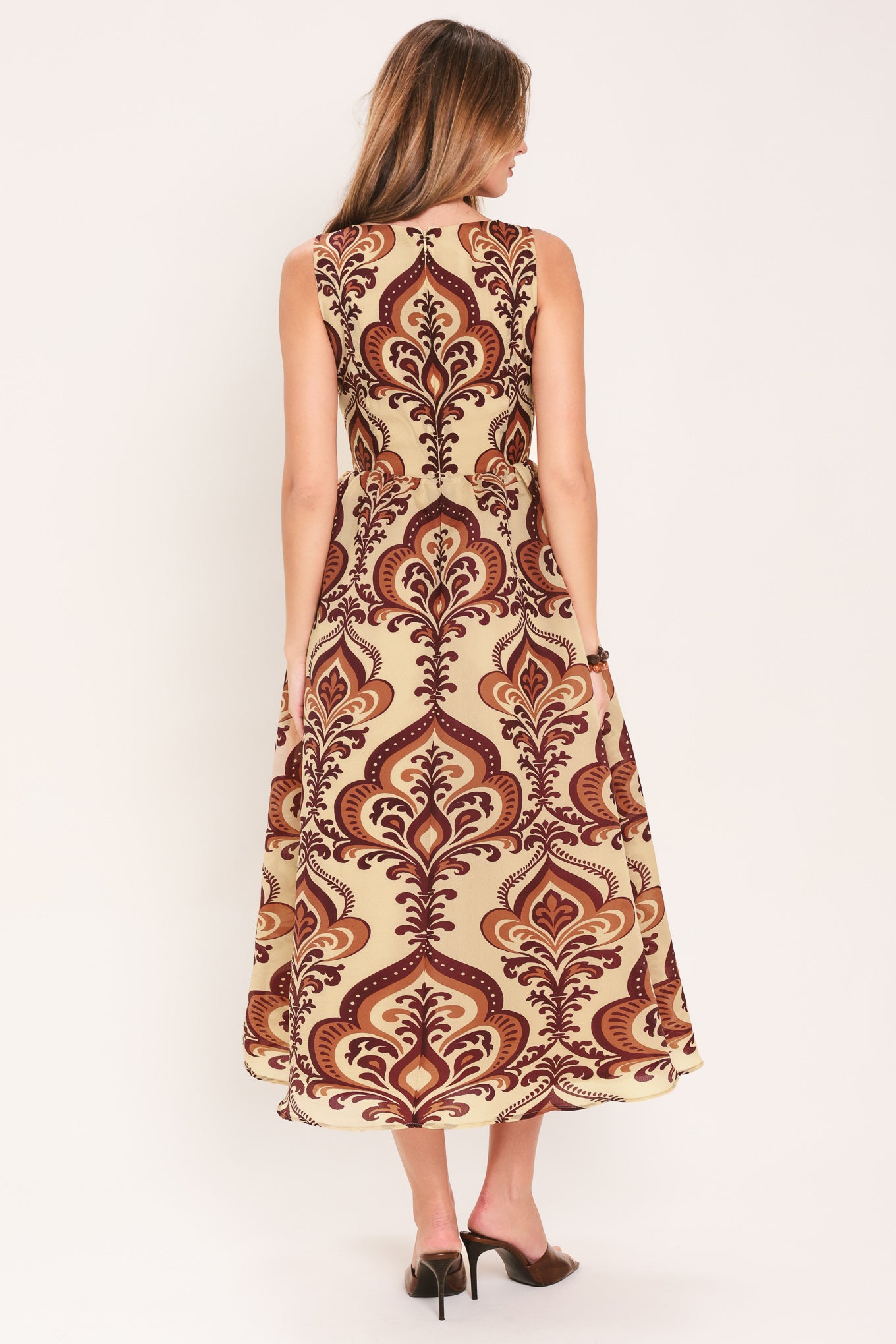 Woman wearing a taupe patterned  midi dress featuring round neckline, sleeveless, full skirt and back zipper closure | Flying Tomato
