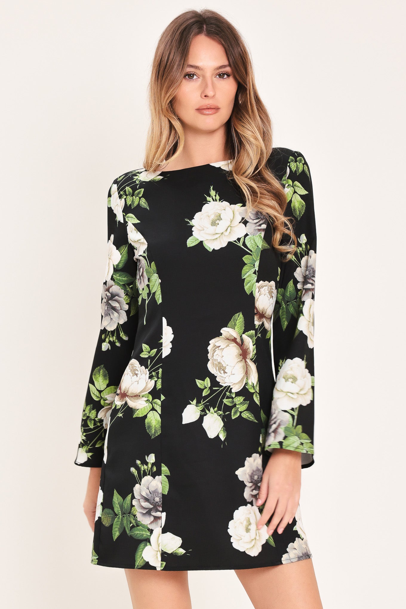 Woman wearing a black with white floral pattern mini dress with wide neckline, long bell sleeve and back zipper closure | Flying Tomato
