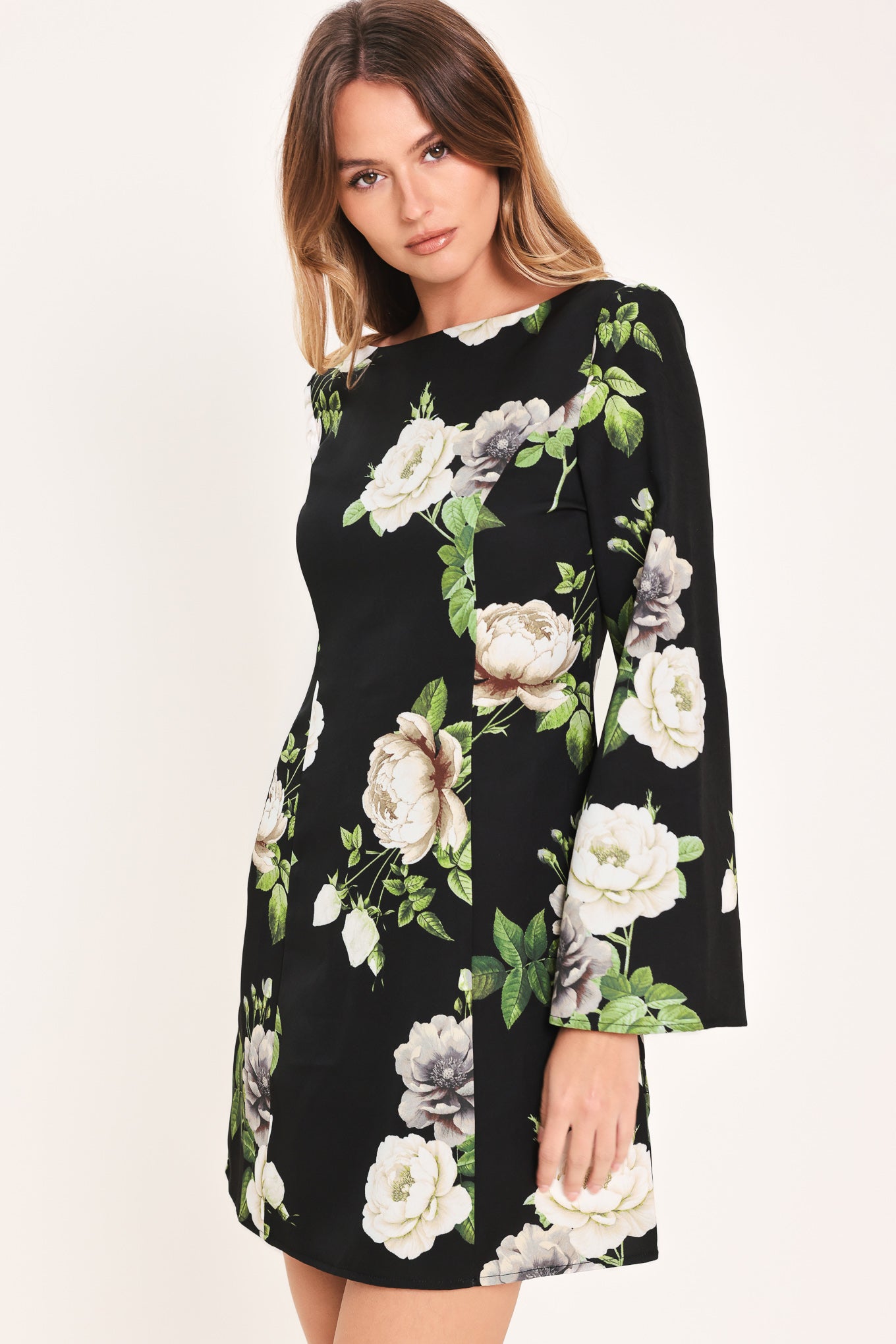 Woman wearing a black with white floral pattern mini dress with wide neckline, long bell sleeve and back zipper closure | Flying Tomato