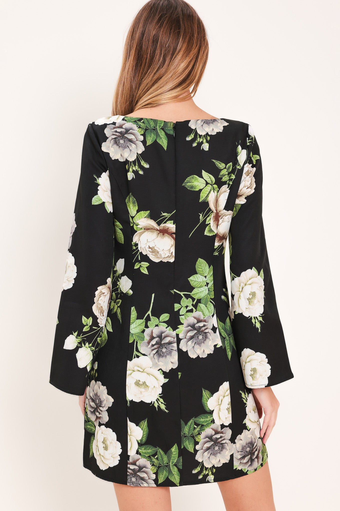 Woman wearing a black with white floral pattern mini dress with wide neckline, long bell sleeve and back zipper closure | Flying Tomato