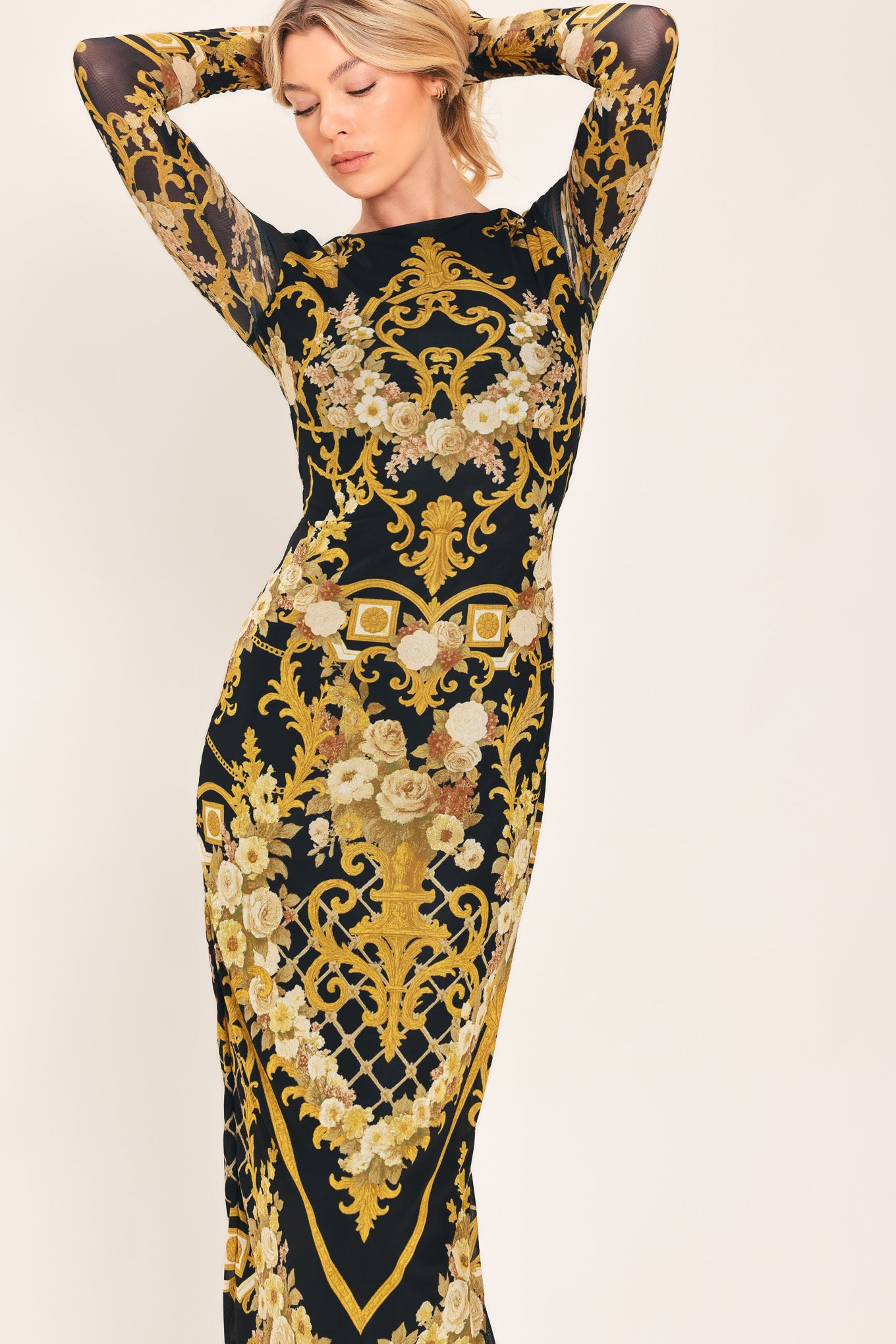 Woman wearing a black and gold baroque printed power mesh midi dress with long sleeve and back neck button | Flying Tomato