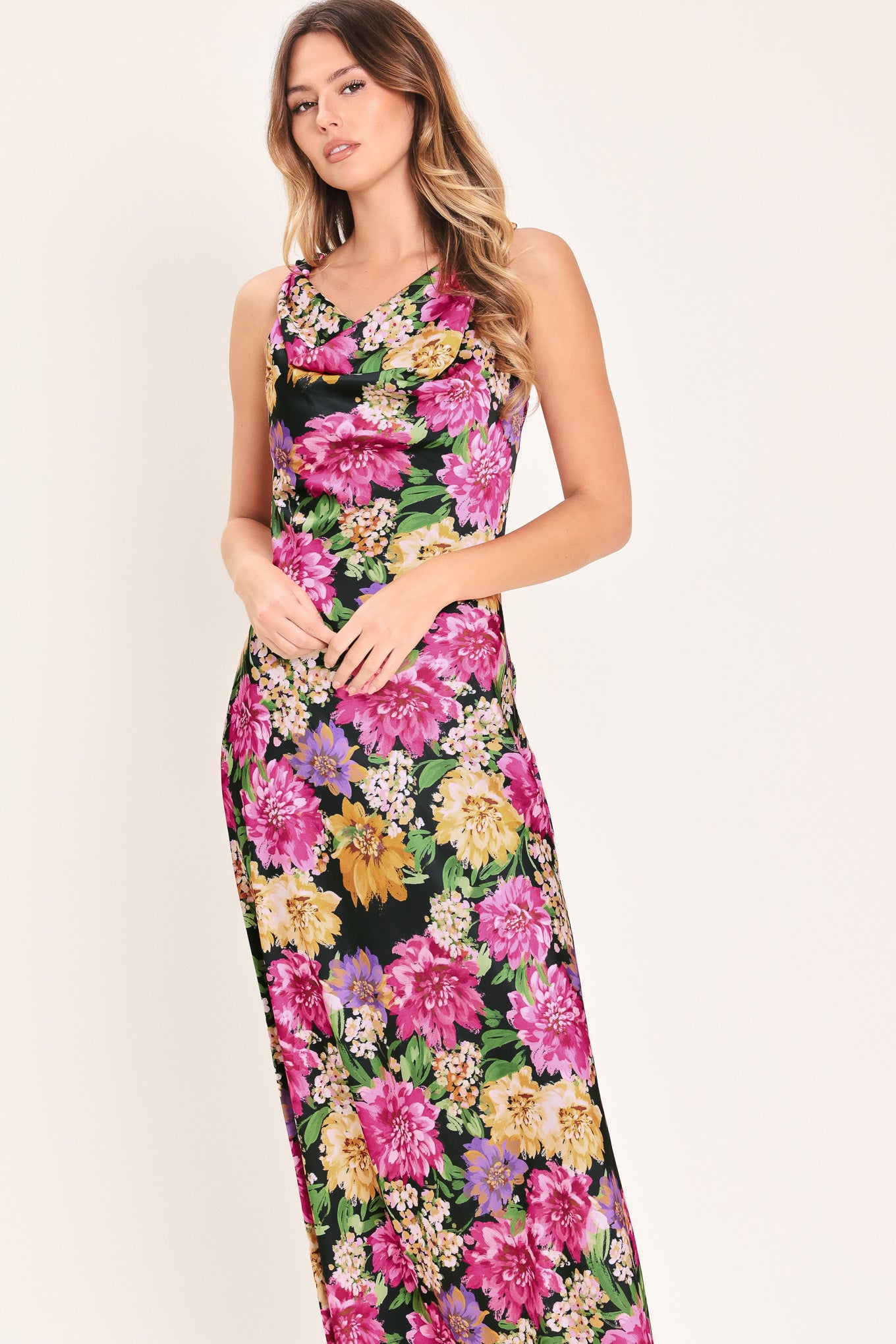 Woman wearing a multicolor pink, yellow, and green floral midi dress with cowl neck and side zipper closure | Flying Tomato