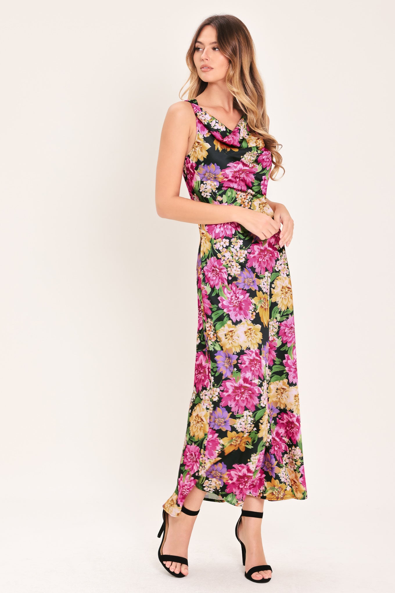 Woman wearing a multicolor pink, yellow, and green floral midi dress with cowl neck and side zipper closure | Flying Tomato