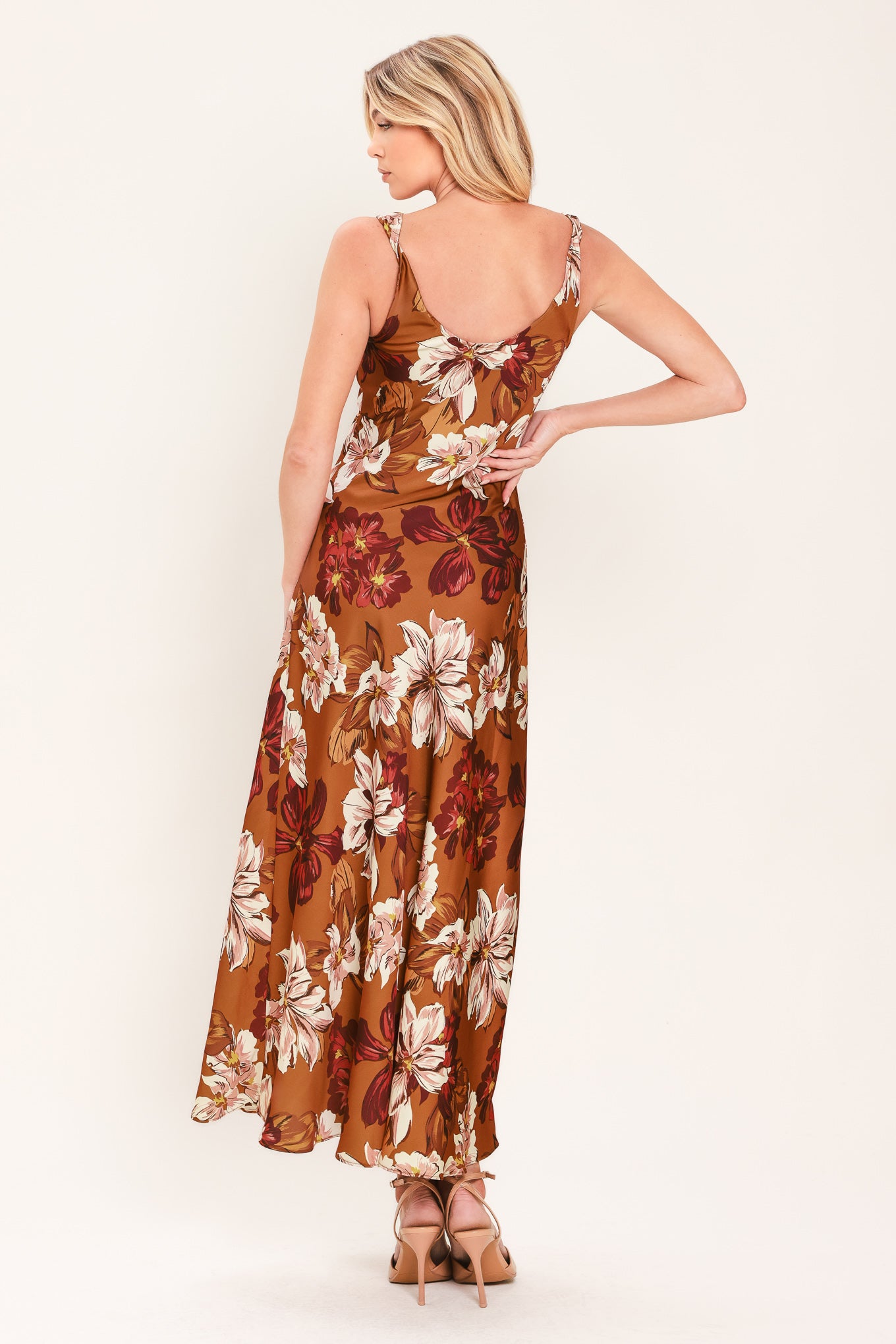 Woman wearing a caramel colored with floral printed woven midi dress featuring cowl neckline, sleeveless, circle skirt and twisted strap at back | Flying Tomato
