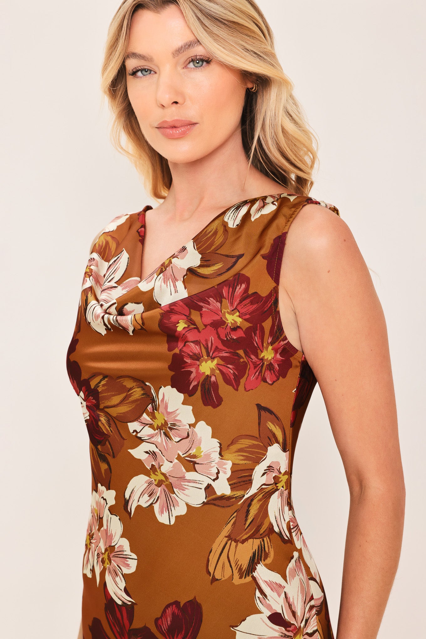 Woman wearing a caramel colored with floral printed woven midi dress featuring cowl neckline, sleeveless, circle skirt and twisted strap at back | Flying Tomato