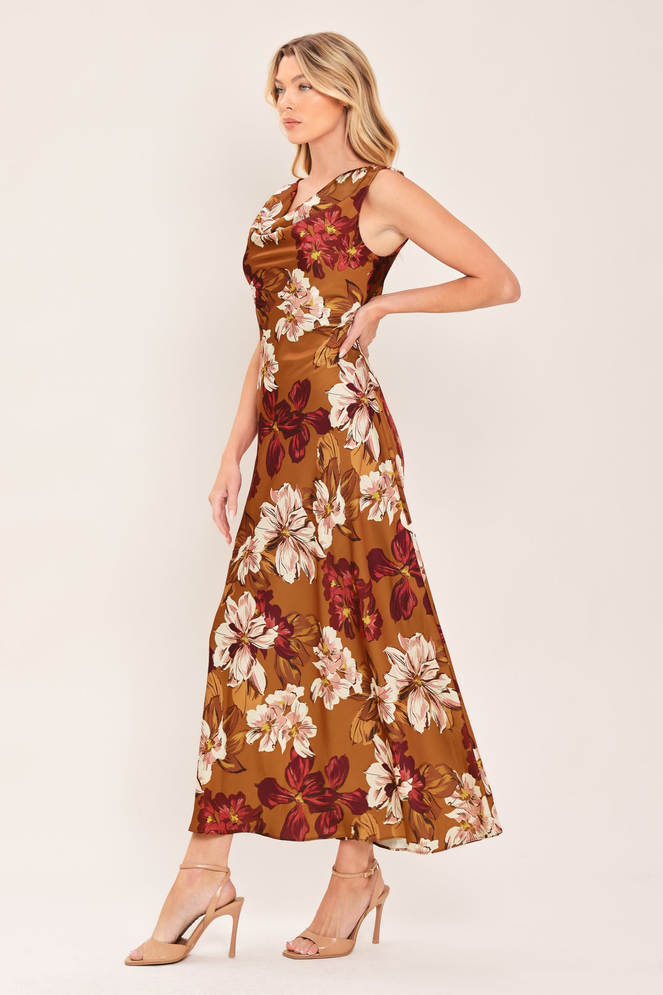 Woman wearing a caramel colored with floral printed woven midi dress featuring cowl neckline, sleeveless, circle skirt and twisted strap at back | Flying Tomato