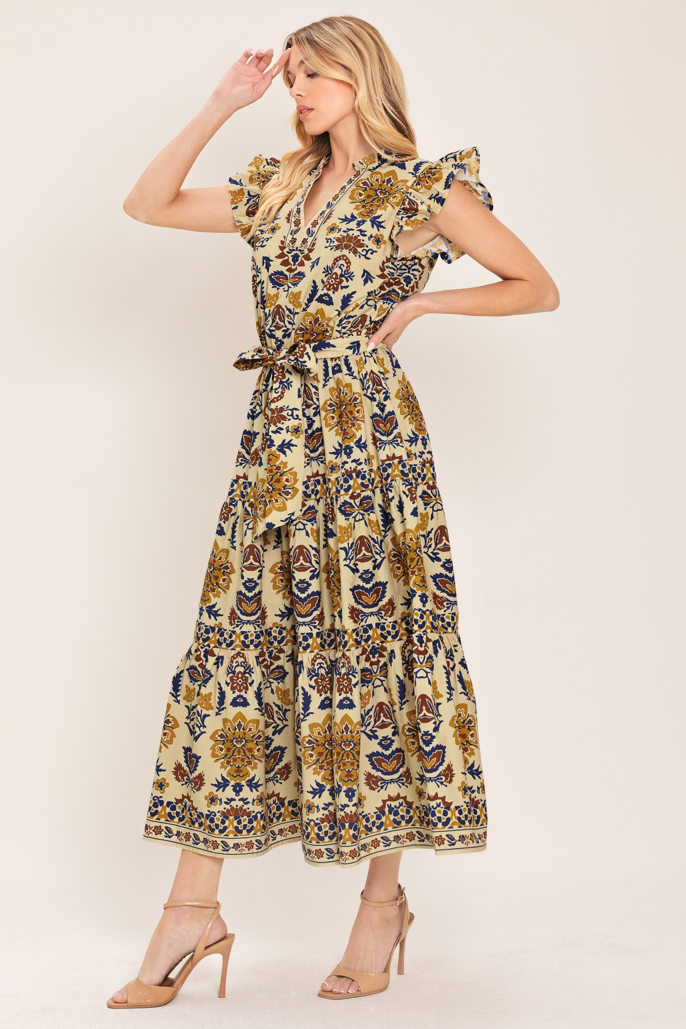 Woman wearing a taupe printed midi dress featuring V neckline with ruffled edge, short ruffle sleeve, elastic waist, self sash and tier skirt | Flying Tomato
