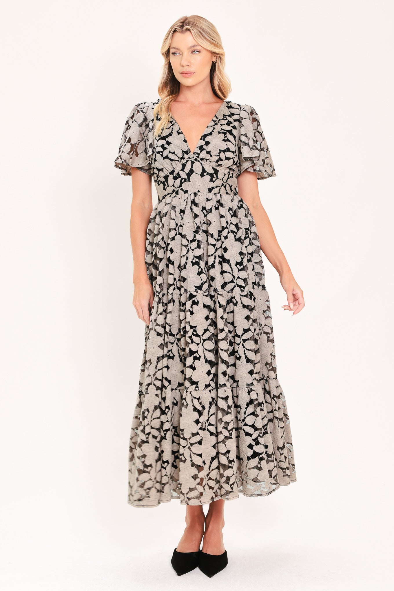 A woman modeling a long-sleeved midi dress with a black and taupe abstract floral pattern | Flying Tomato