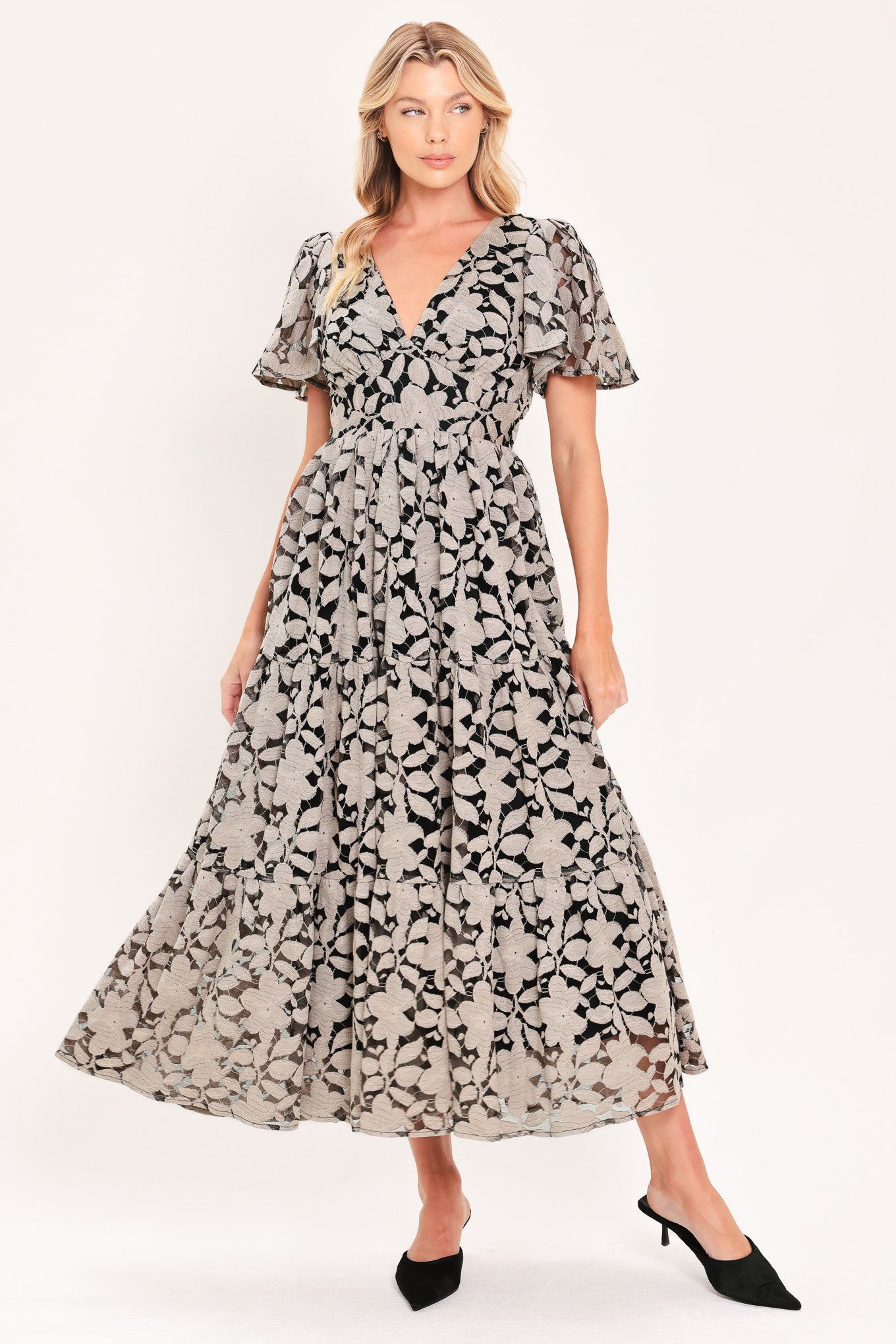 A woman modeling a long-sleeved midi dress with a black and taupe abstract floral pattern | Flying Tomato