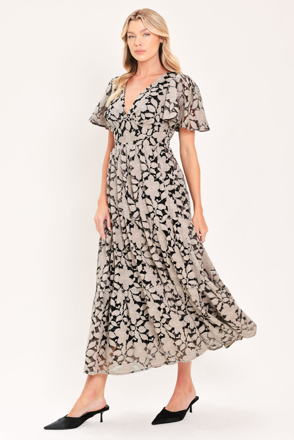 A woman modeling a long-sleeved midi dress with a black and taupe abstract floral pattern | Flying Tomato