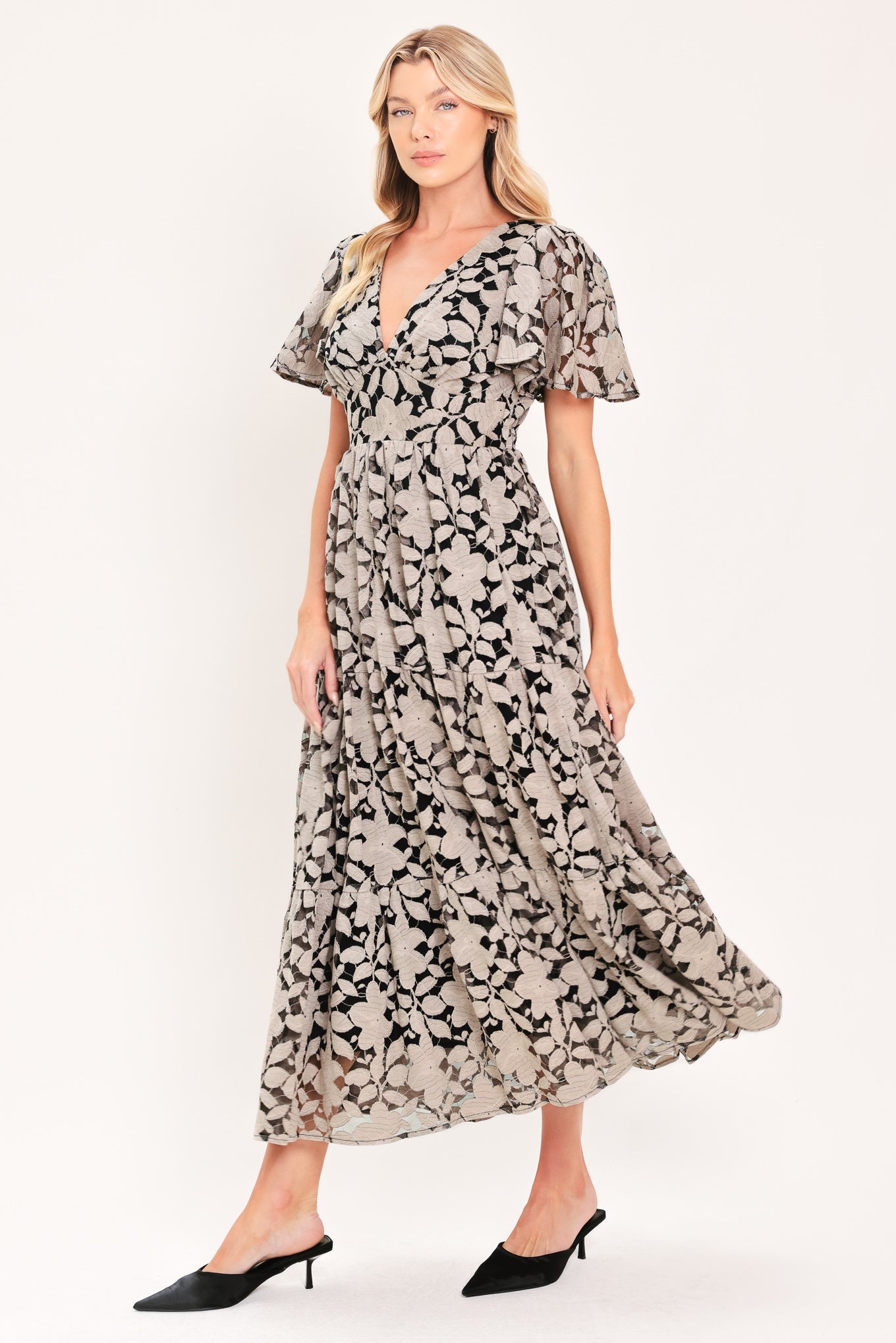 A woman modeling a long-sleeved midi dress with a black and taupe abstract floral pattern | Flying Tomato