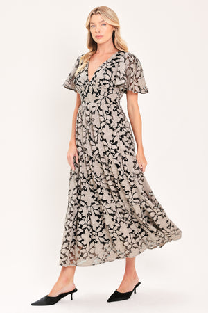 A woman modeling a long-sleeved midi dress with a black and taupe abstract floral pattern | Flying Tomato