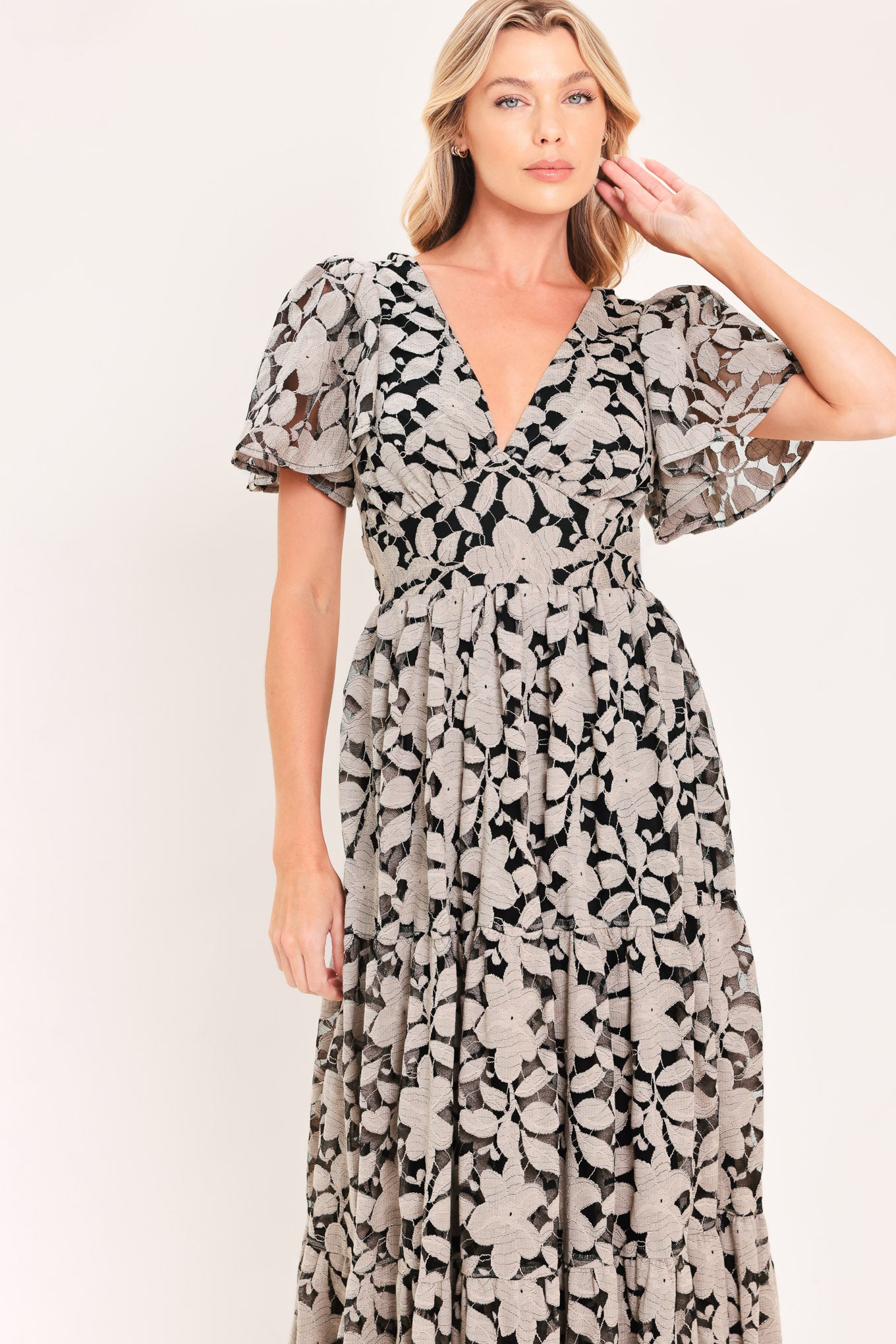 A woman modeling a long-sleeved midi dress with a black and taupe abstract floral pattern | Flying Tomato
