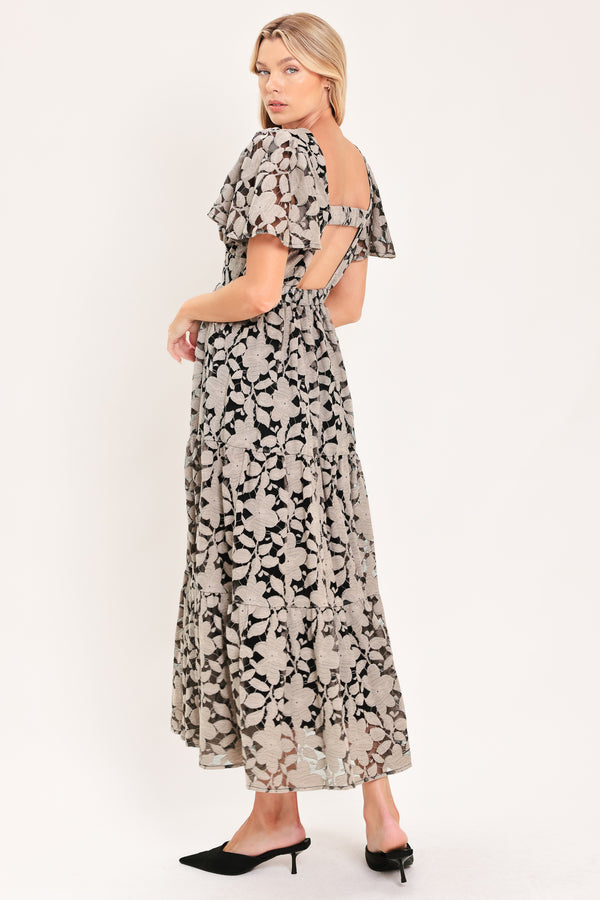 A woman modeling a long-sleeved midi dress with a black and taupe abstract floral pattern | Flying Tomato