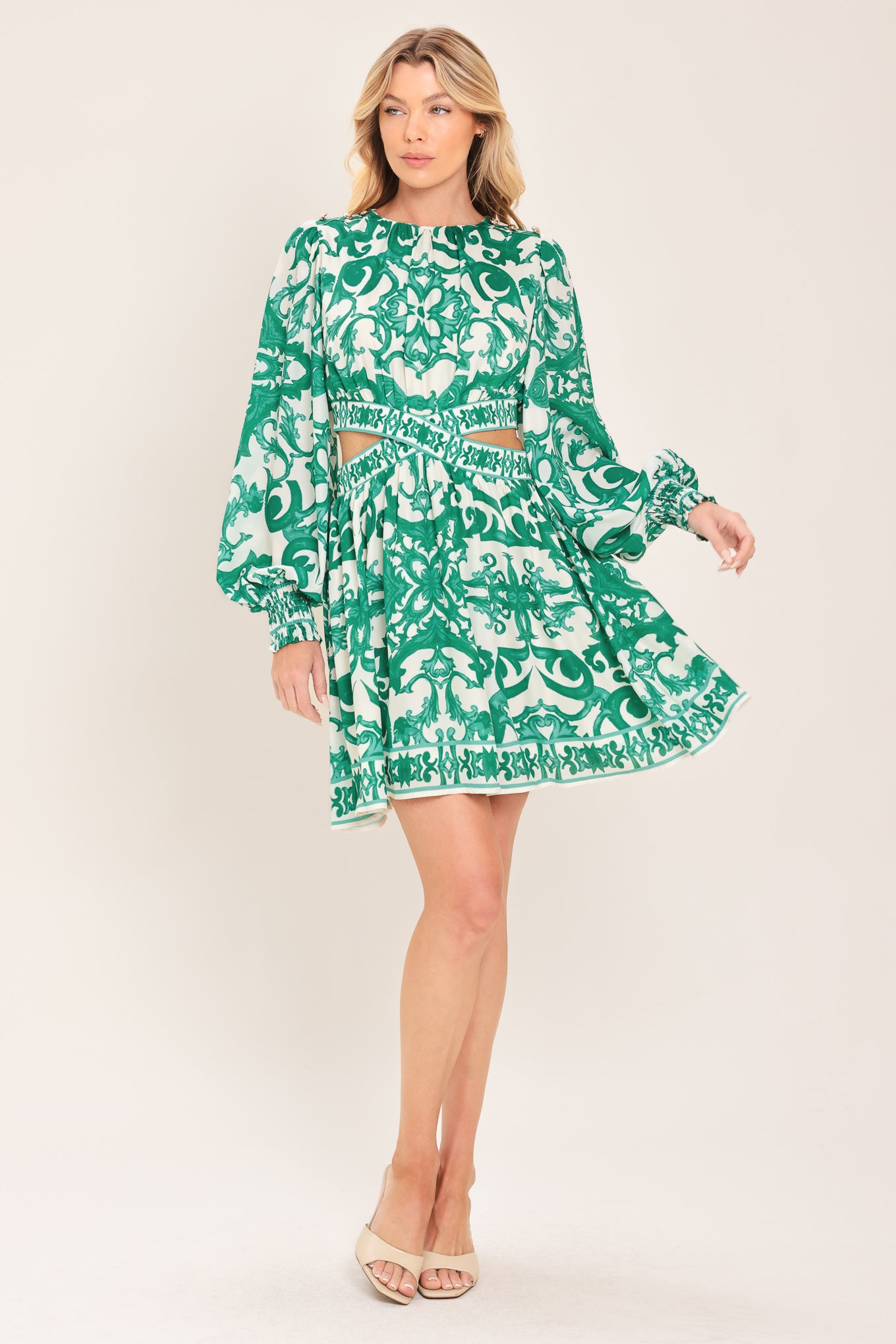 A woman wearing a green and white patterned long-sleeve mini dress with a tie waist and side cutouts| Flying Tomato