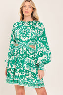 A woman wearing a green and white patterned long-sleeve mini dress with a tie waist and side cutouts| Flying Tomato