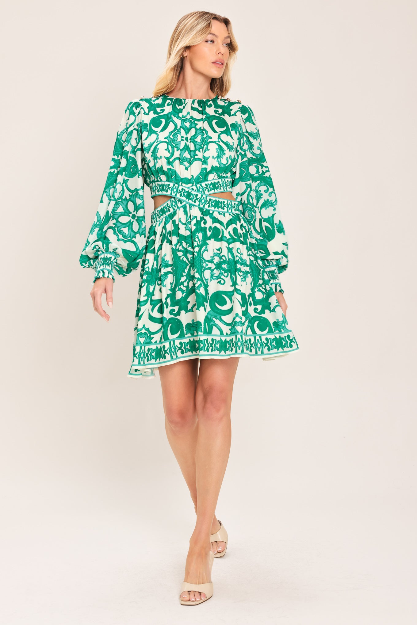 A woman wearing a green and white patterned long-sleeve mini dress with a tie waist and side cutouts| Flying Tomato