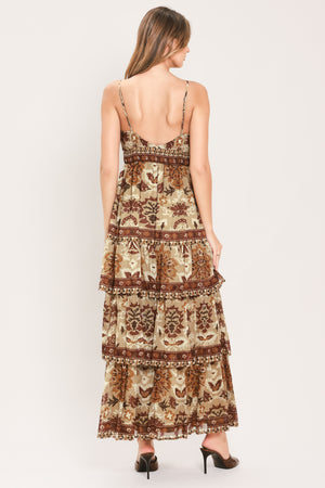 A woman modeling a sleeveless, tiered maxi dress with a bohemian-style floral and geometric pattern in brown and beige | Flying Tomato