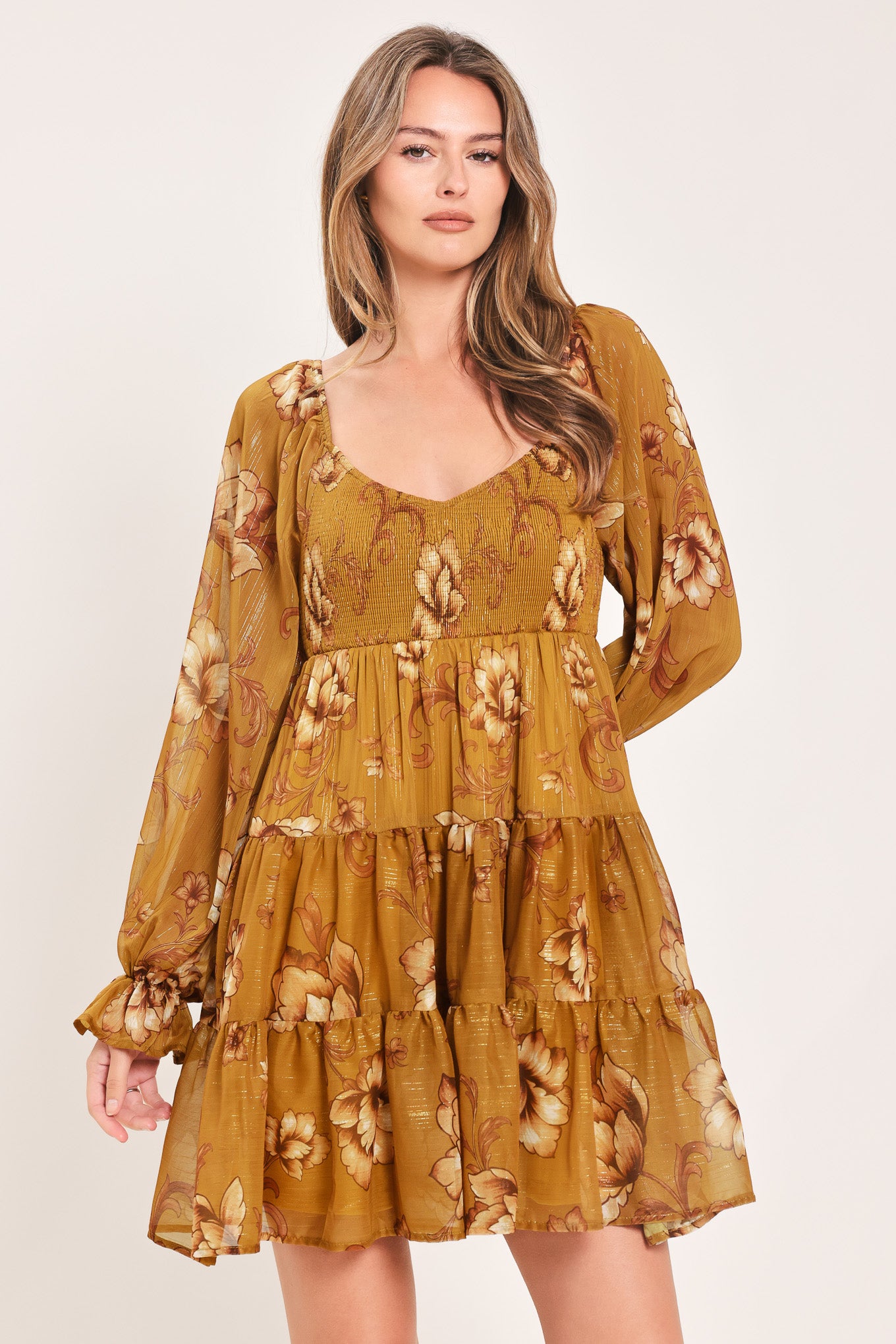 A woman modeling a mustard yellow mini dress with a beige floral pattern, long balloon sleeves, and a V-neckline | FREEMARKET