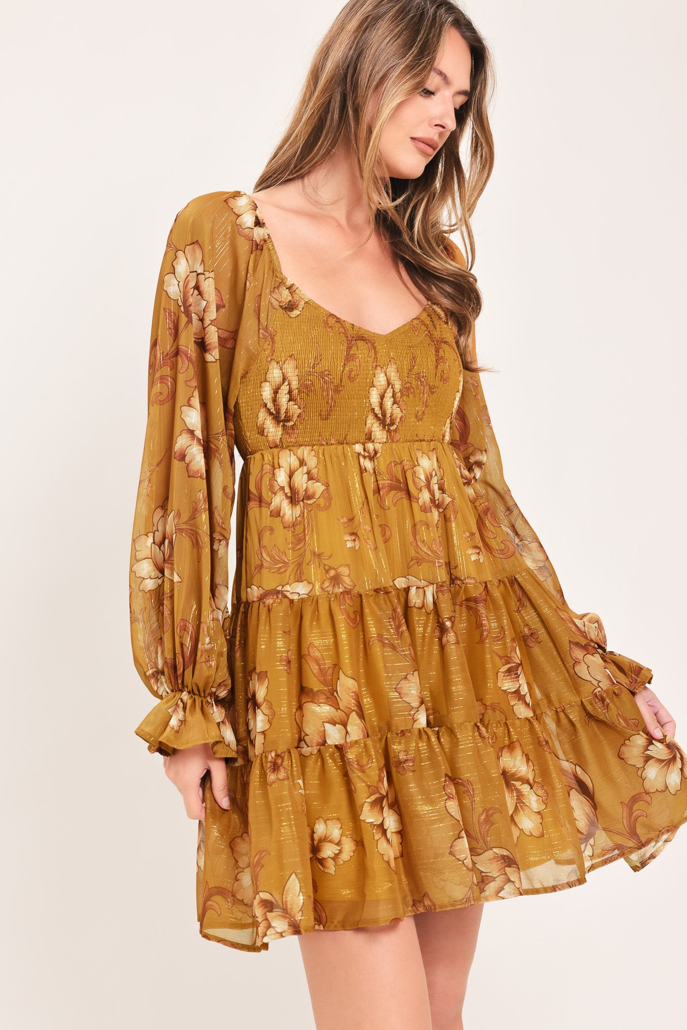A woman modeling a mustard yellow mini dress with a beige floral pattern, long balloon sleeves, and a V-neckline | FREEMARKET