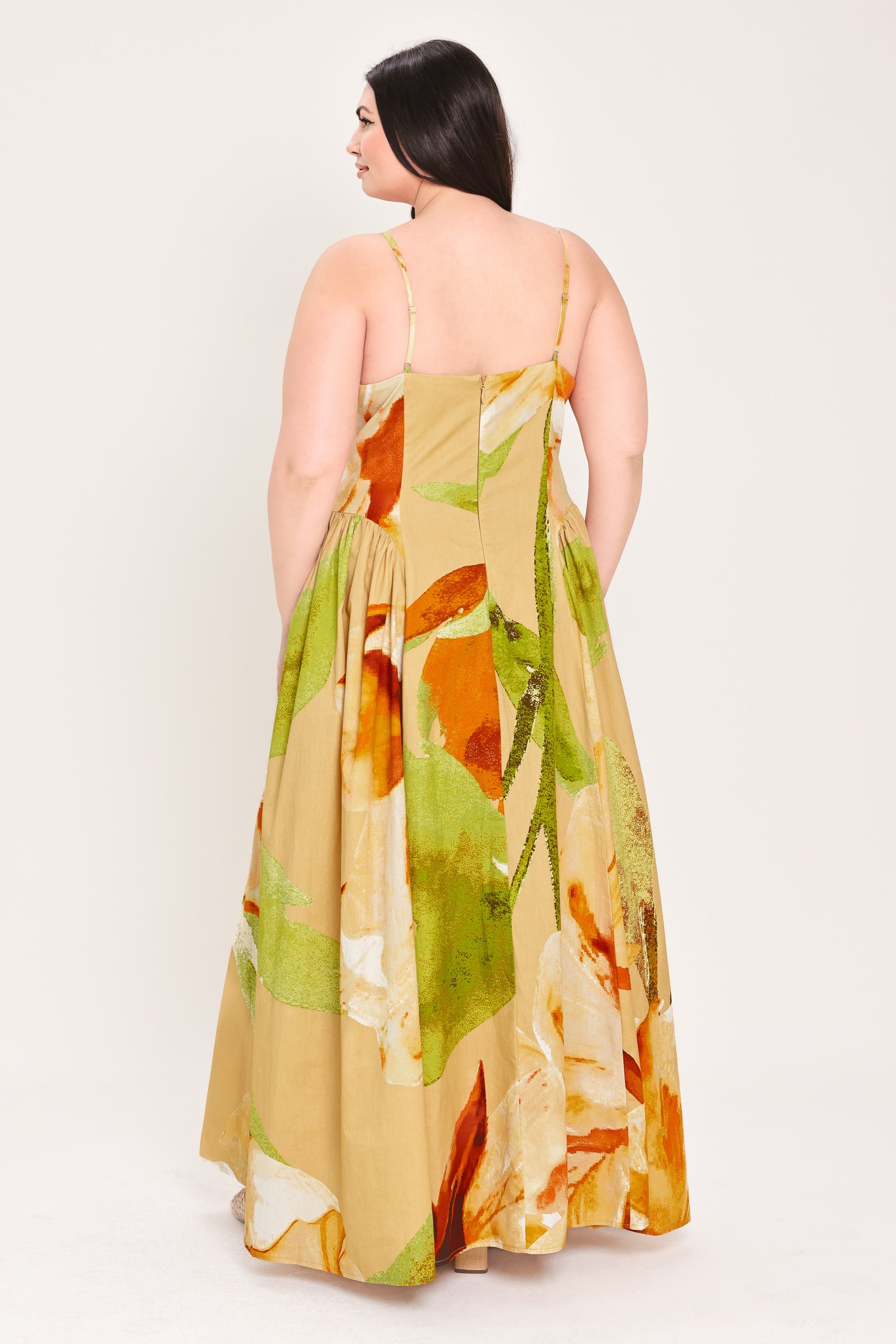 Woman wearing a green with brown and khaki floral printed maxi dress featuring bustier top, straps, side shirring detail and back zipper closure | Flying Tomato