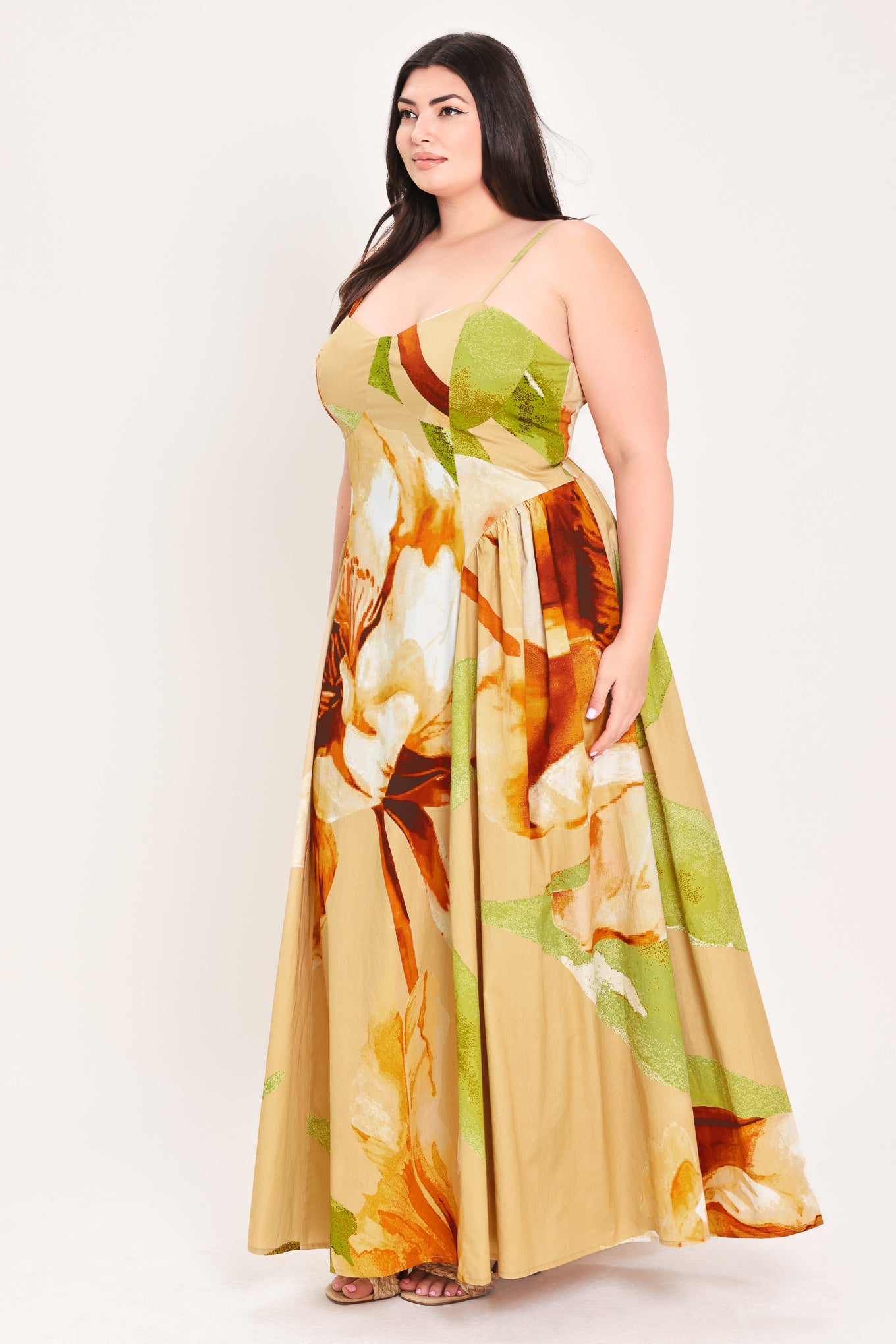 Woman wearing a green with brown and khaki floral printed maxi dress featuring bustier top, straps, side shirring detail and back zipper closure | Flying Tomato