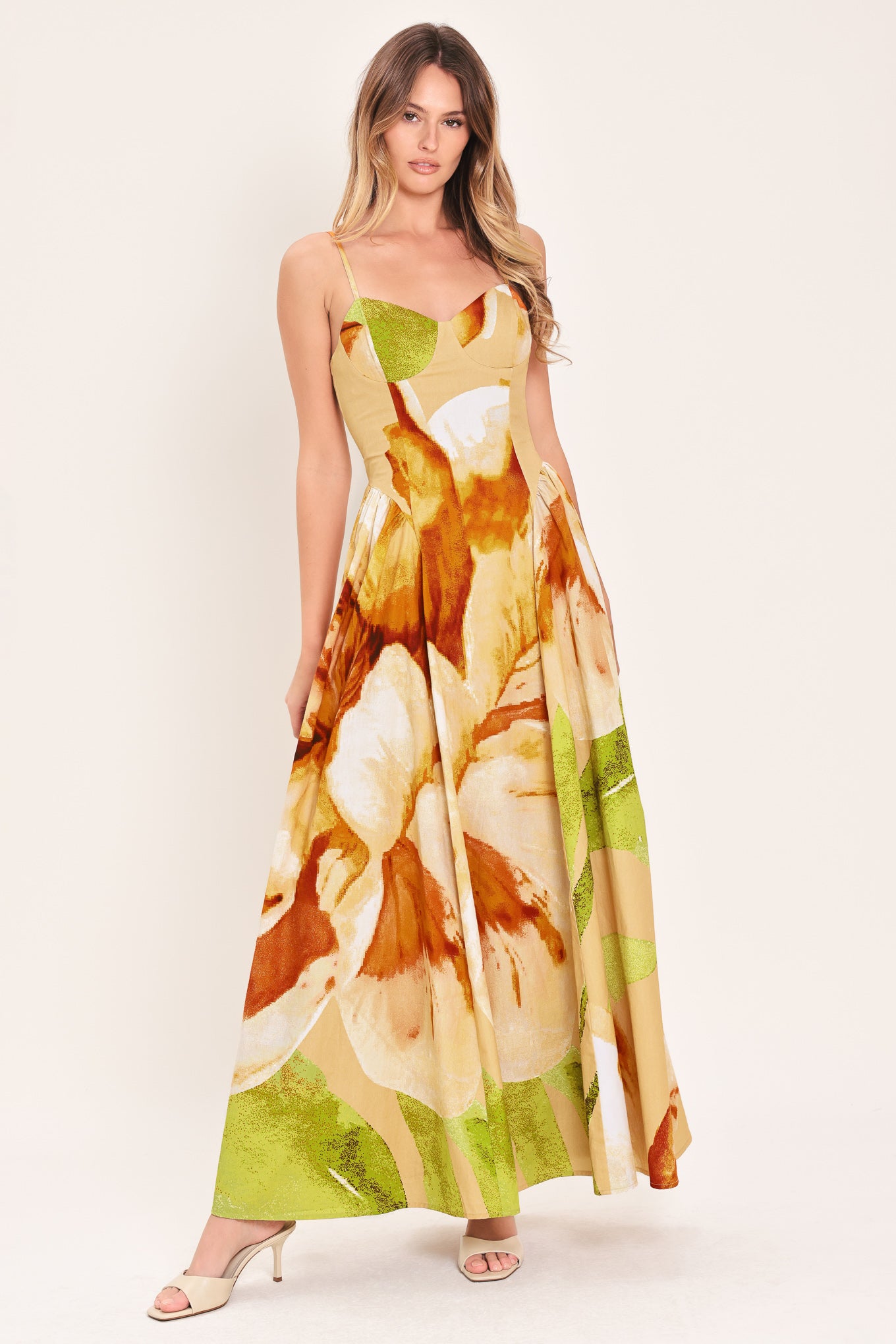 Woman wearing a green with brown and khaki floral printed maxi dress featuring bustier top, straps, side shirring detail and back zipper closure | Flying Tomato