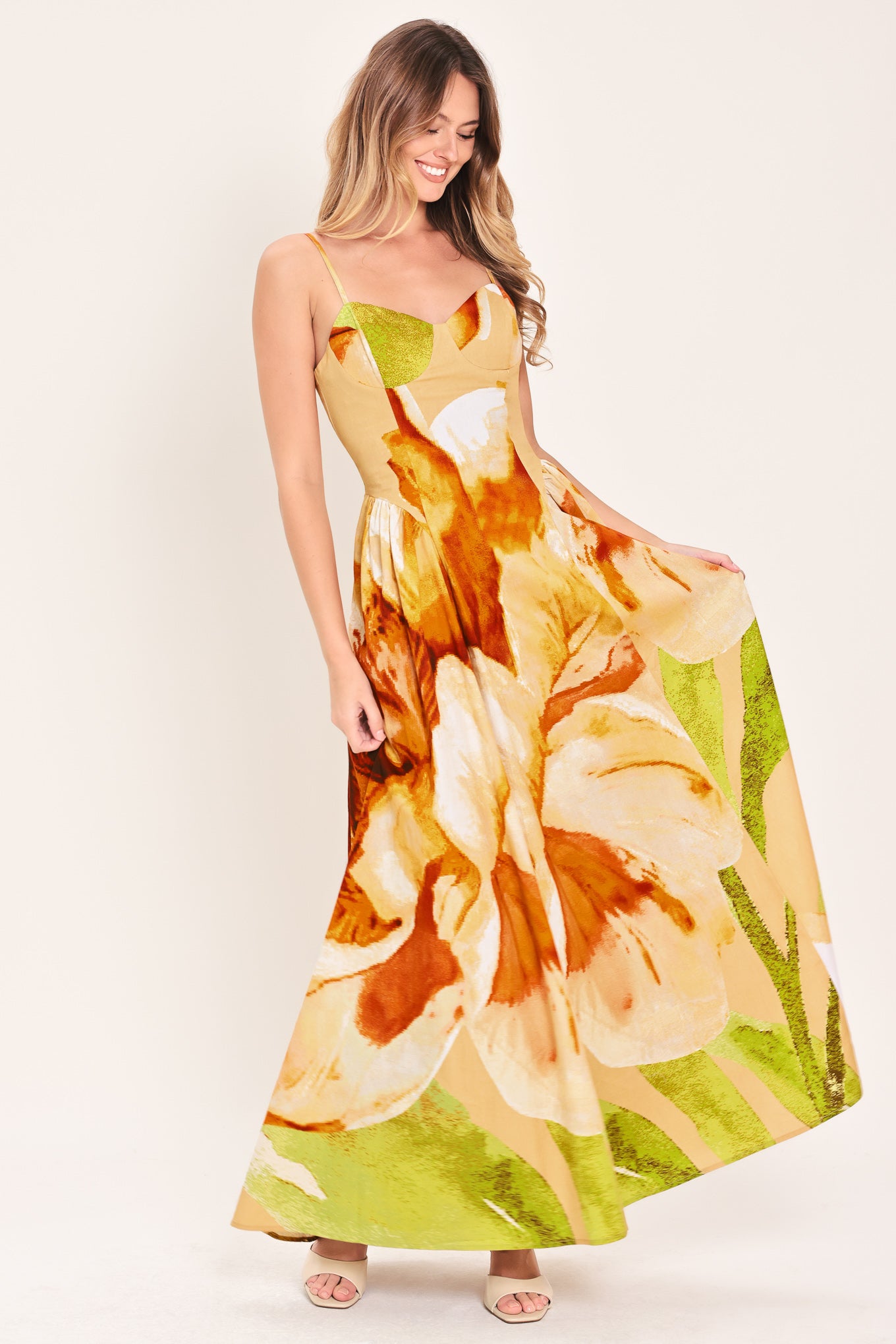 Woman wearing a green with brown and khaki floral printed maxi dress featuring bustier top, straps, side shirring detail and back zipper closure | Flying Tomato