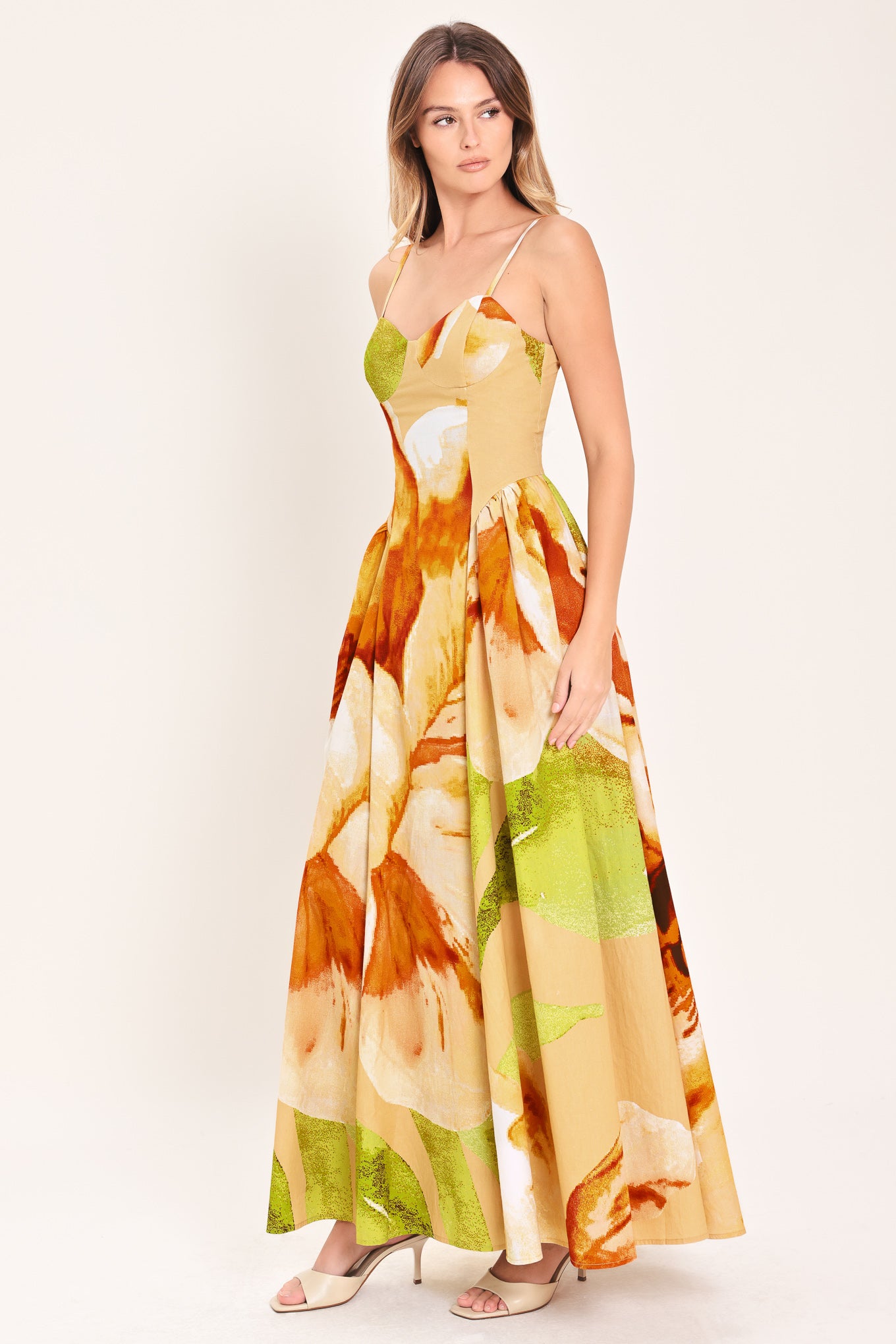 Woman wearing a green with brown and khaki floral printed maxi dress featuring bustier top, straps, side shirring detail and back zipper closure | Flying Tomato
