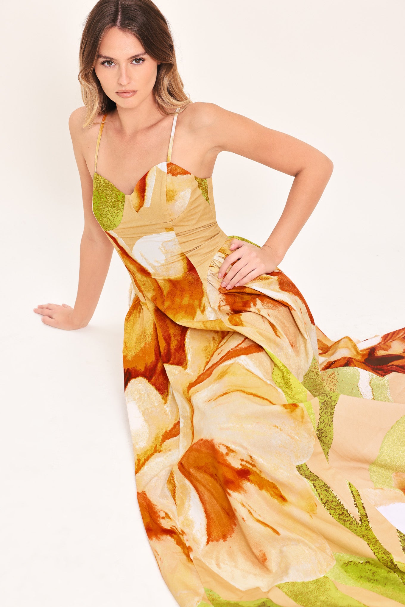 Woman wearing a green with brown and khaki floral printed maxi dress featuring bustier top, straps, side shirring detail and back zipper closure | Flying Tomato
