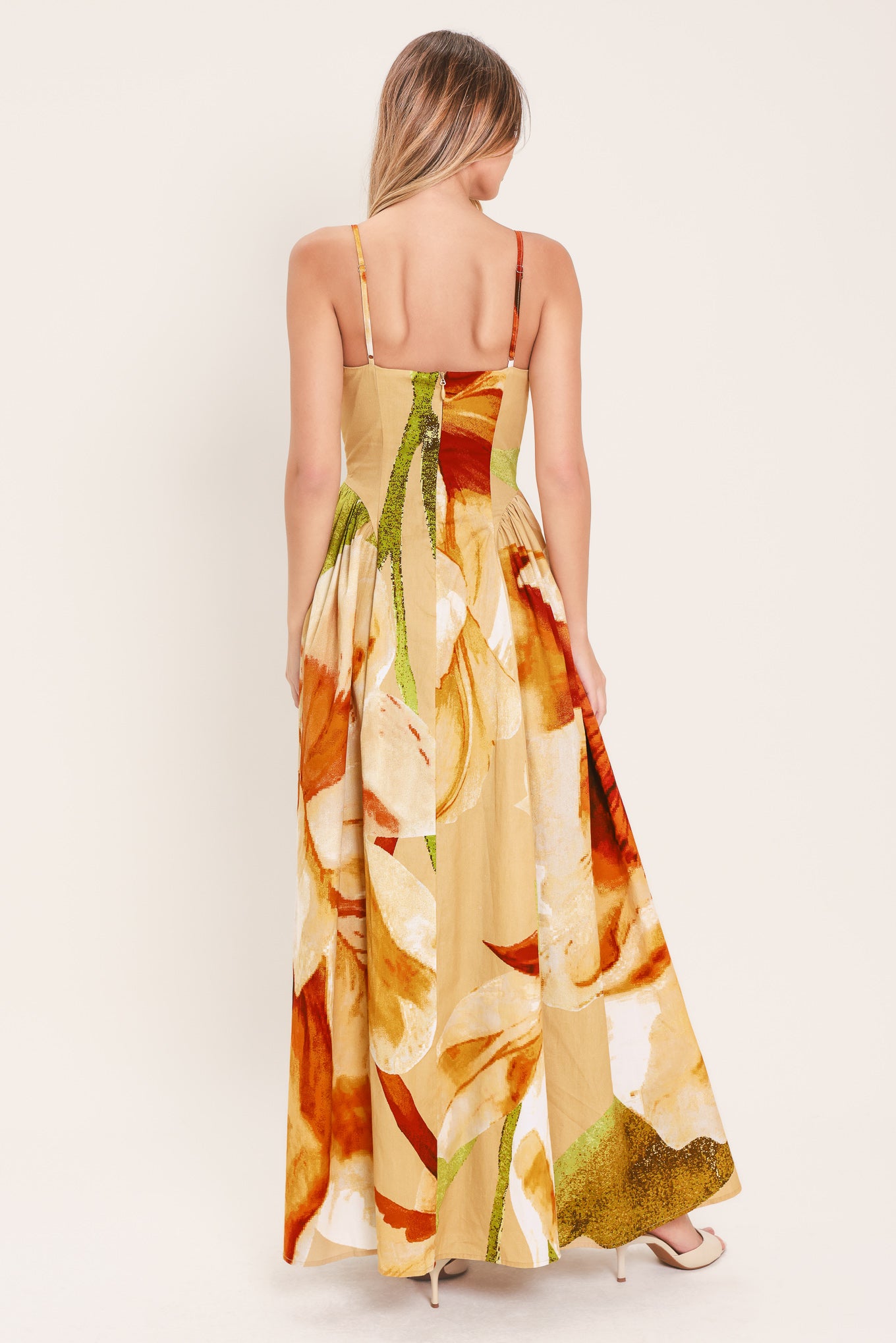 Woman wearing a green with brown and khaki floral printed maxi dress featuring bustier top, straps, side shirring detail and back zipper closure | Flying Tomato