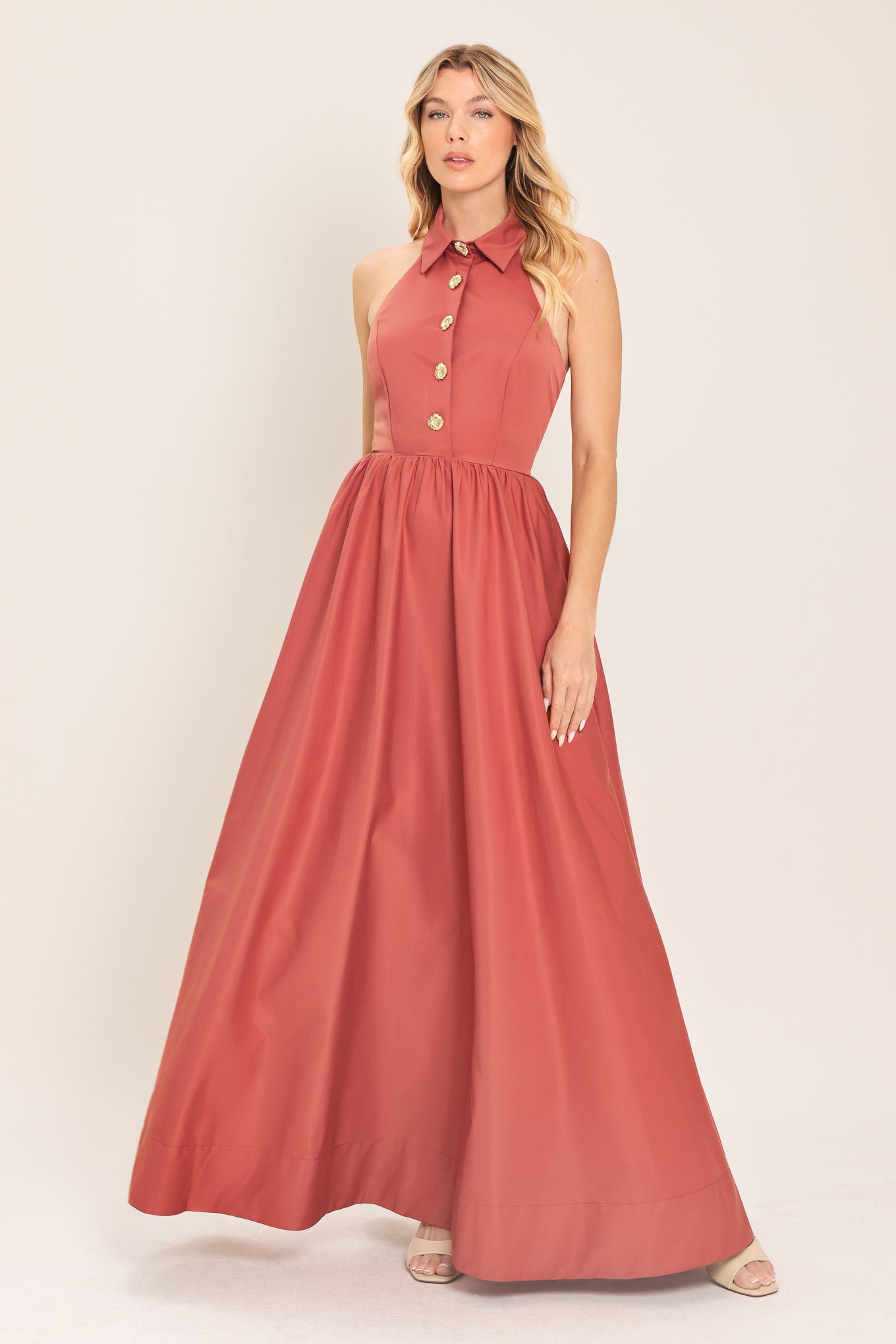 Woman wearing a long sienna colored maxi dress with buttons maxi dress featuring halter neckline with collared finish, full skirt and bare back with zipper closure | Flying Tomato
