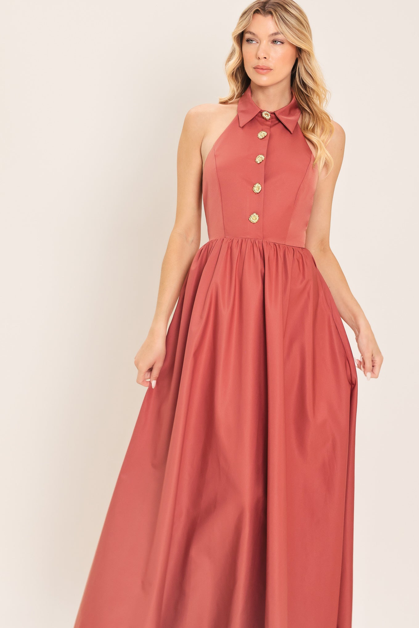 Woman wearing a long sienna colored maxi dress with buttons maxi dress featuring halter neckline with collared finish, full skirt and bare back with zipper closure | Flying Tomato