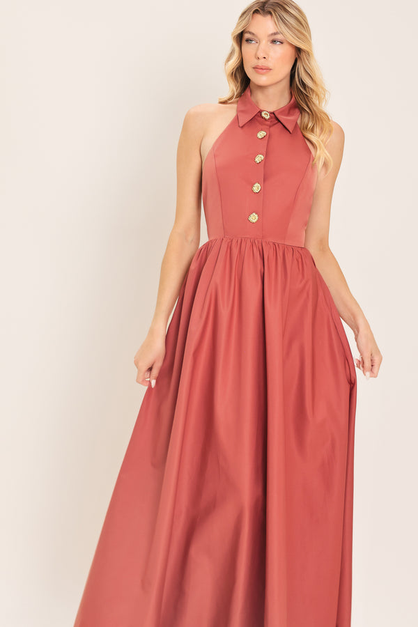 Woman wearing a long sienna colored maxi dress with buttons maxi dress featuring halter neckline with collared finish, full skirt and bare back with zipper closure | Flying Tomato