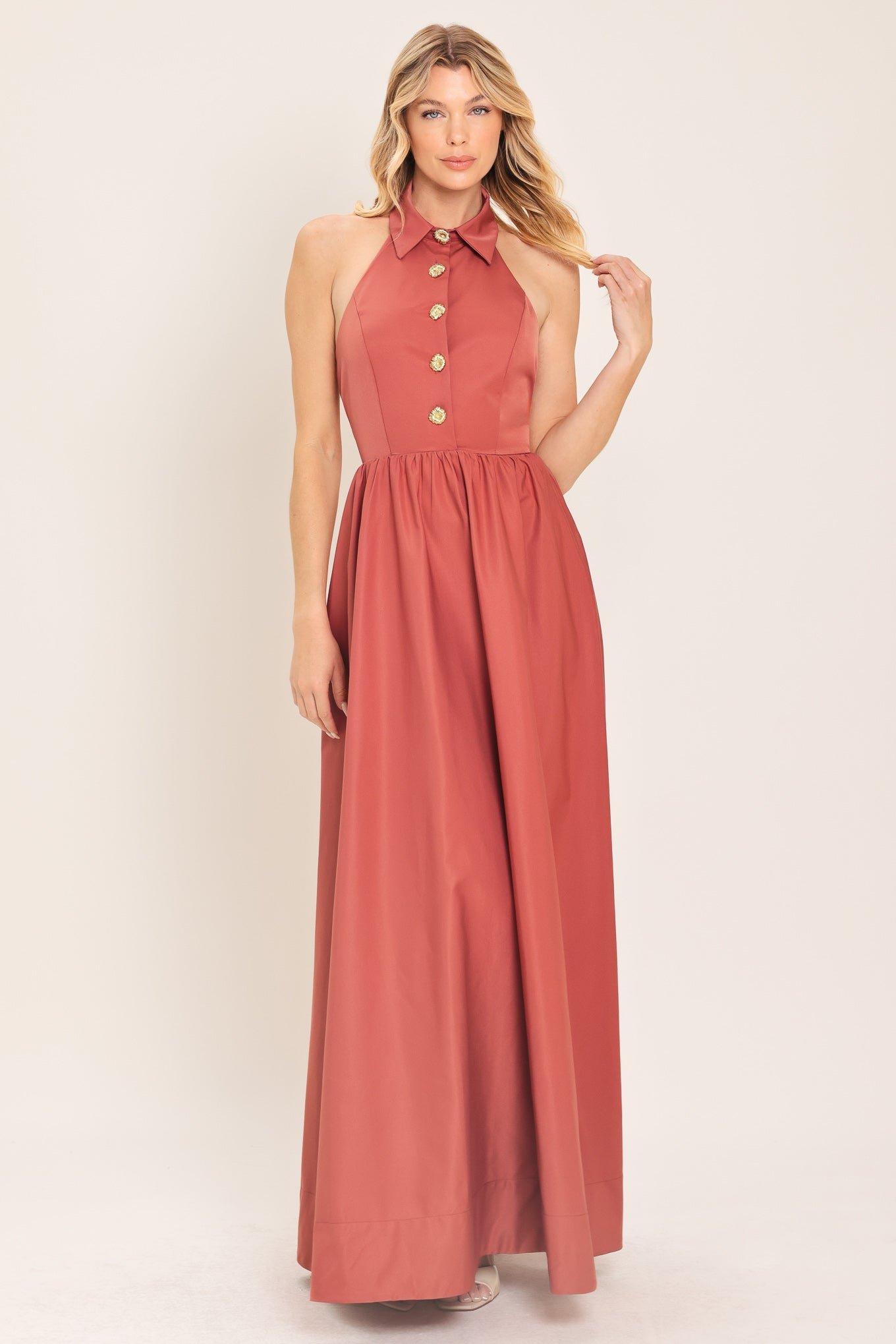 Woman wearing a long sienna colored maxi dress with buttons maxi dress featuring halter neckline with collared finish, full skirt and bare back with zipper closure | Flying Tomato