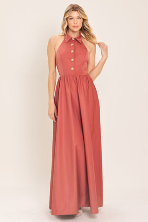 Woman wearing a long sienna colored maxi dress with buttons maxi dress featuring halter neckline with collared finish, full skirt and bare back with zipper closure | Flying Tomato