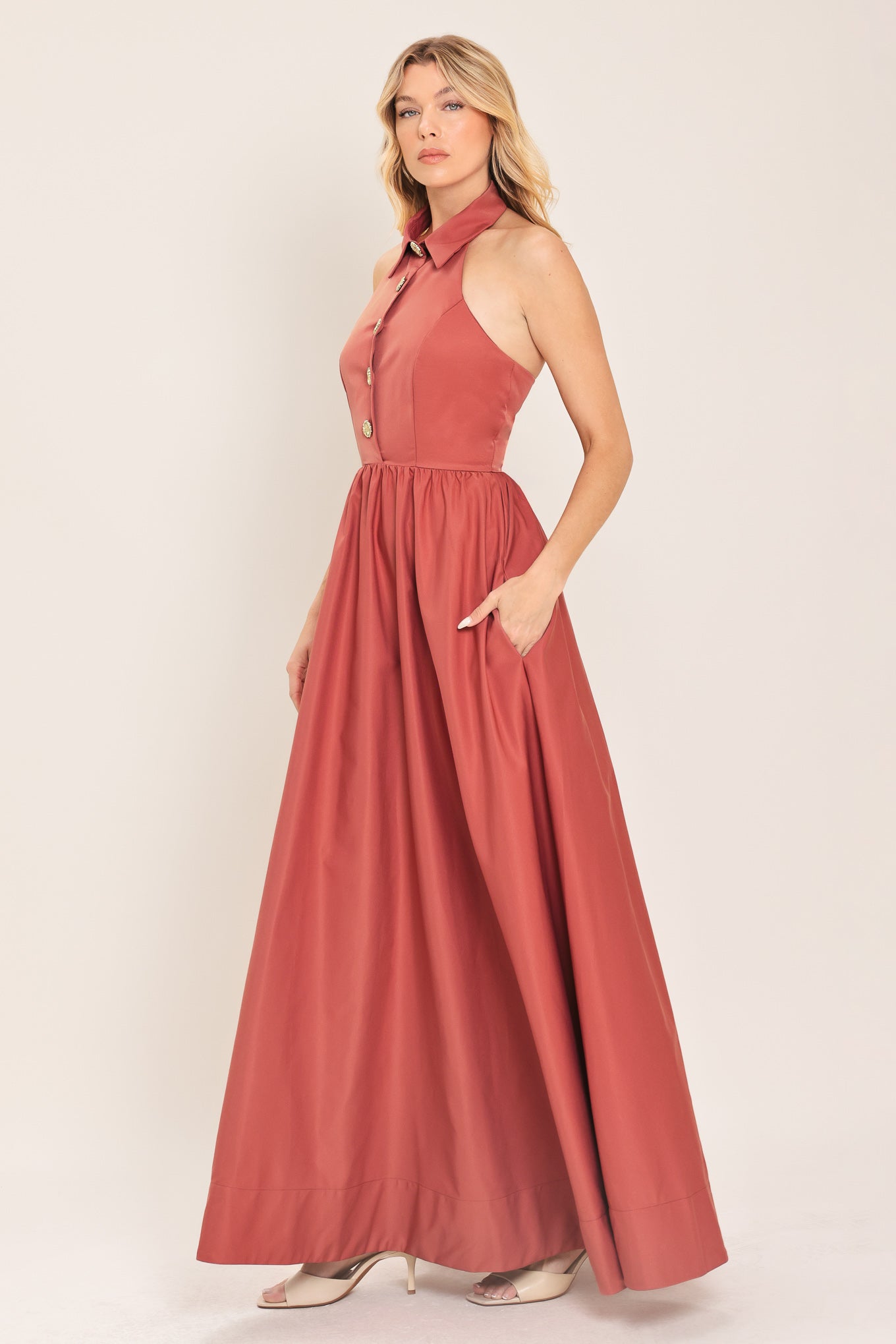 Woman wearing a long sienna colored maxi dress with buttons maxi dress featuring halter neckline with collared finish, full skirt and bare back with zipper closure | Flying Tomato