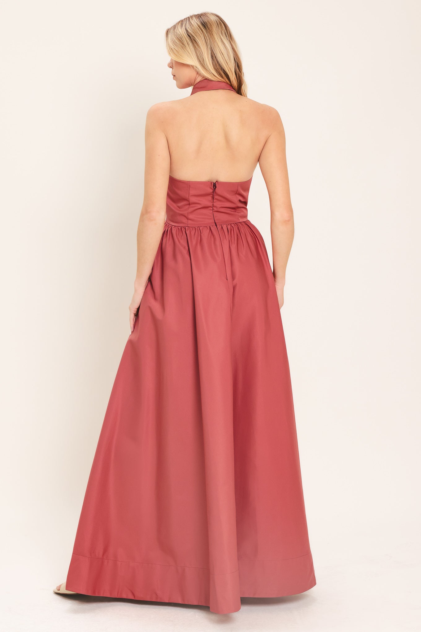 Woman wearing a long sienna colored maxi dress with buttons maxi dress featuring halter neckline with collared finish, full skirt and bare back with zipper closure | Flying Tomato