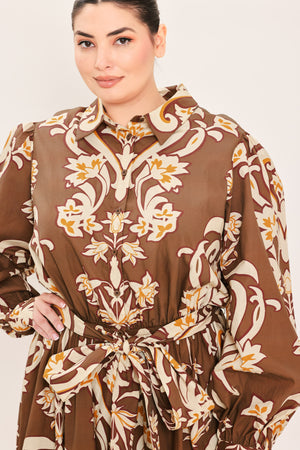 A woman modeling a brown long-sleeve midi dress with a cream and gold baroque-style floral pattern, featuring a tie waist belt and a shawl collar | Plus Curve Flying Tomato