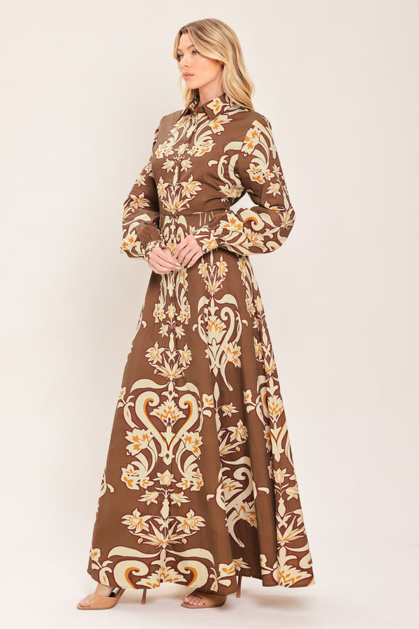 A woman wearing a long-sleeve, high-neck button up maxi dress with a brown base and a beige and gold baroque-style floral pattern | Flying Tomato