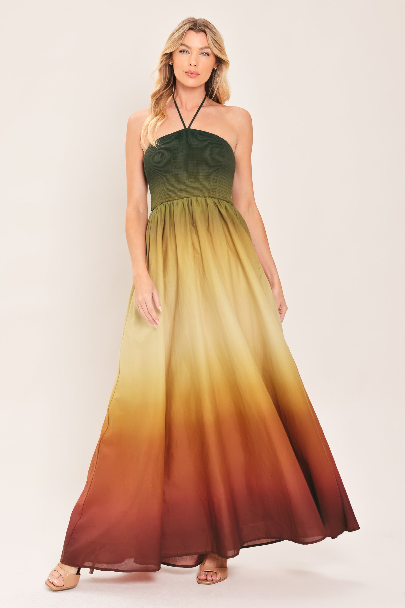 A woman modeling a strapless halter-neck maxi dress with a gradient color-blocked design transitioning from dark green at the bodice to yellow, orange, and brown at the skirt | Flying Tomato