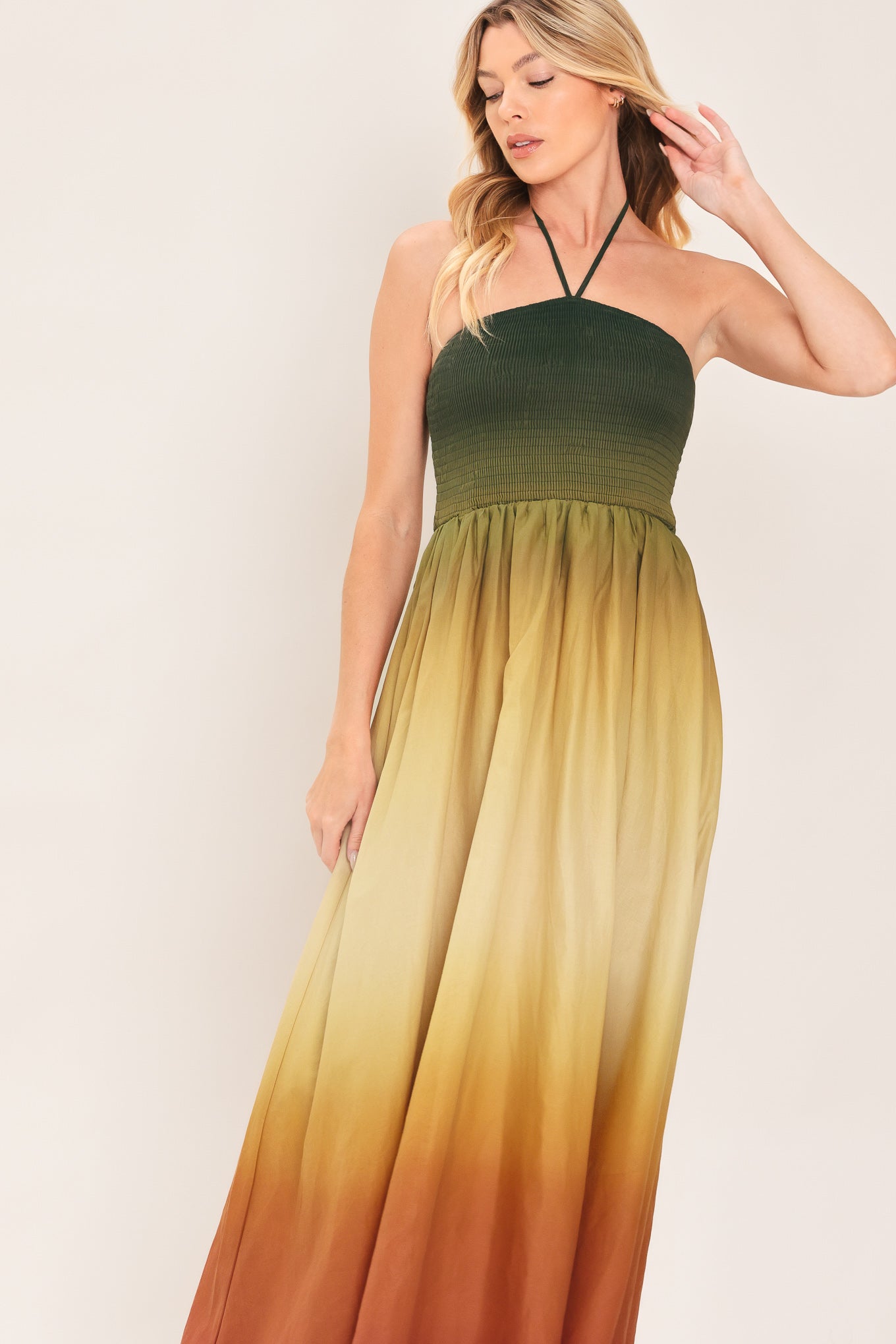 A woman modeling a strapless halter-neck maxi dress with a gradient color-blocked design transitioning from dark green at the bodice to yellow, orange, and brown at the skirt | Flying Tomato