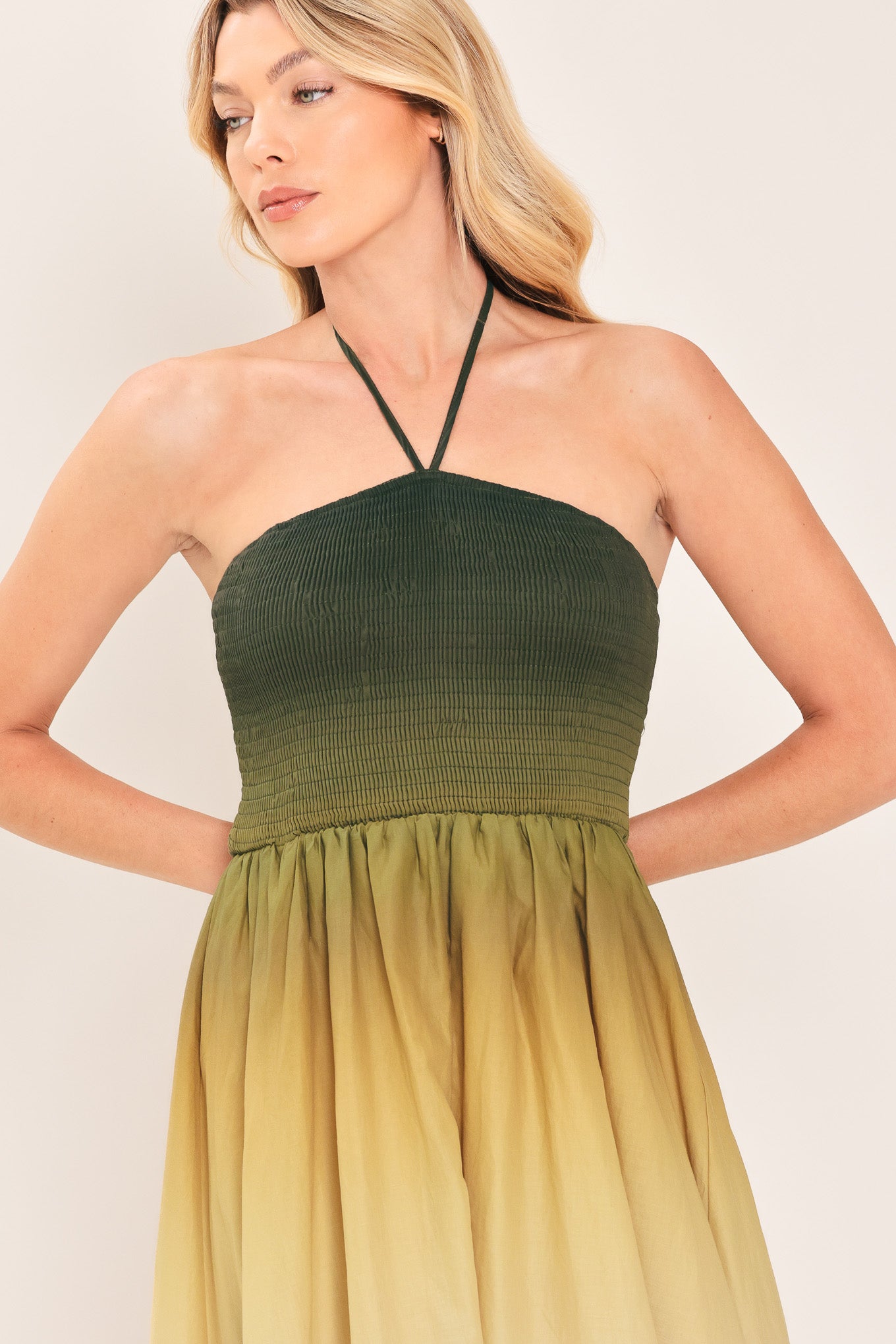 A woman modeling a strapless halter-neck maxi dress with a gradient color-blocked design transitioning from dark green at the bodice to yellow, orange, and brown at the skirt | Flying Tomato