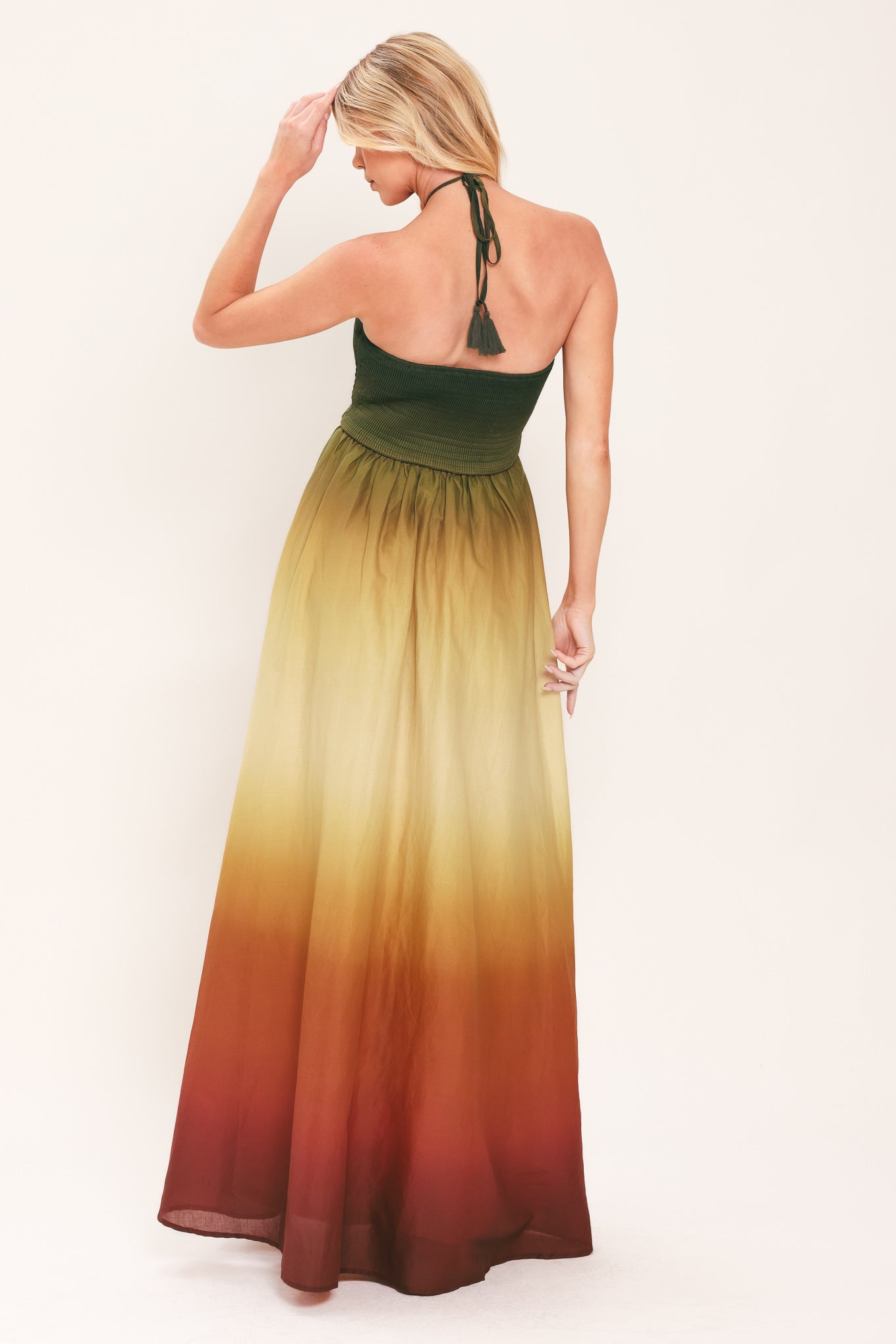 A woman modeling a strapless halter-neck maxi dress with a gradient color-blocked design transitioning from dark green at the bodice to yellow, orange, and brown at the skirt | Flying Tomato