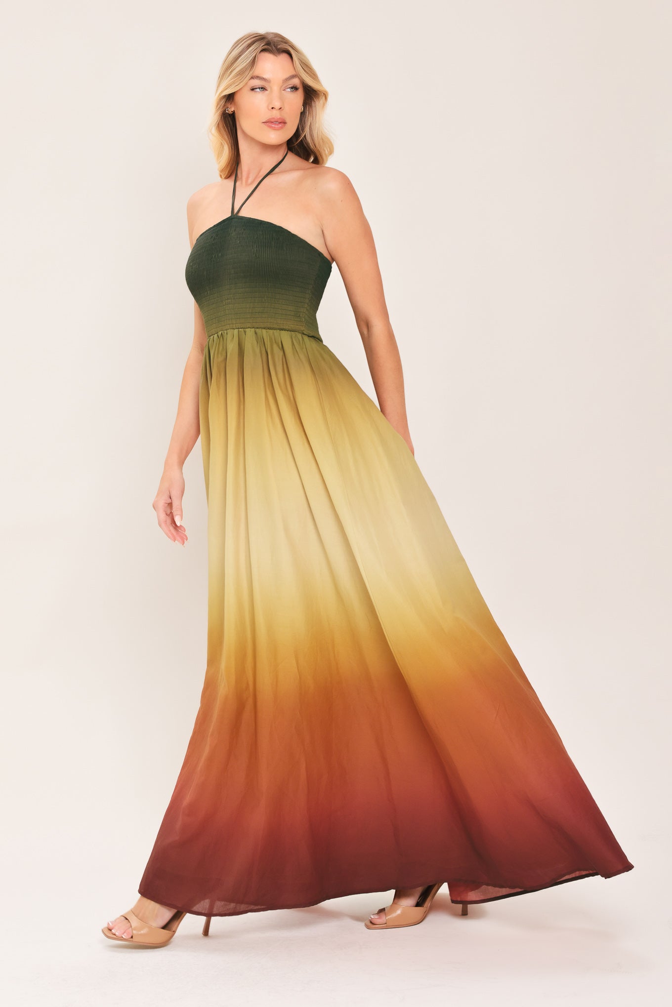 A woman modeling a strapless halter-neck maxi dress with a gradient color-blocked design transitioning from dark green at the bodice to yellow, orange, and brown at the skirt | Flying Tomato