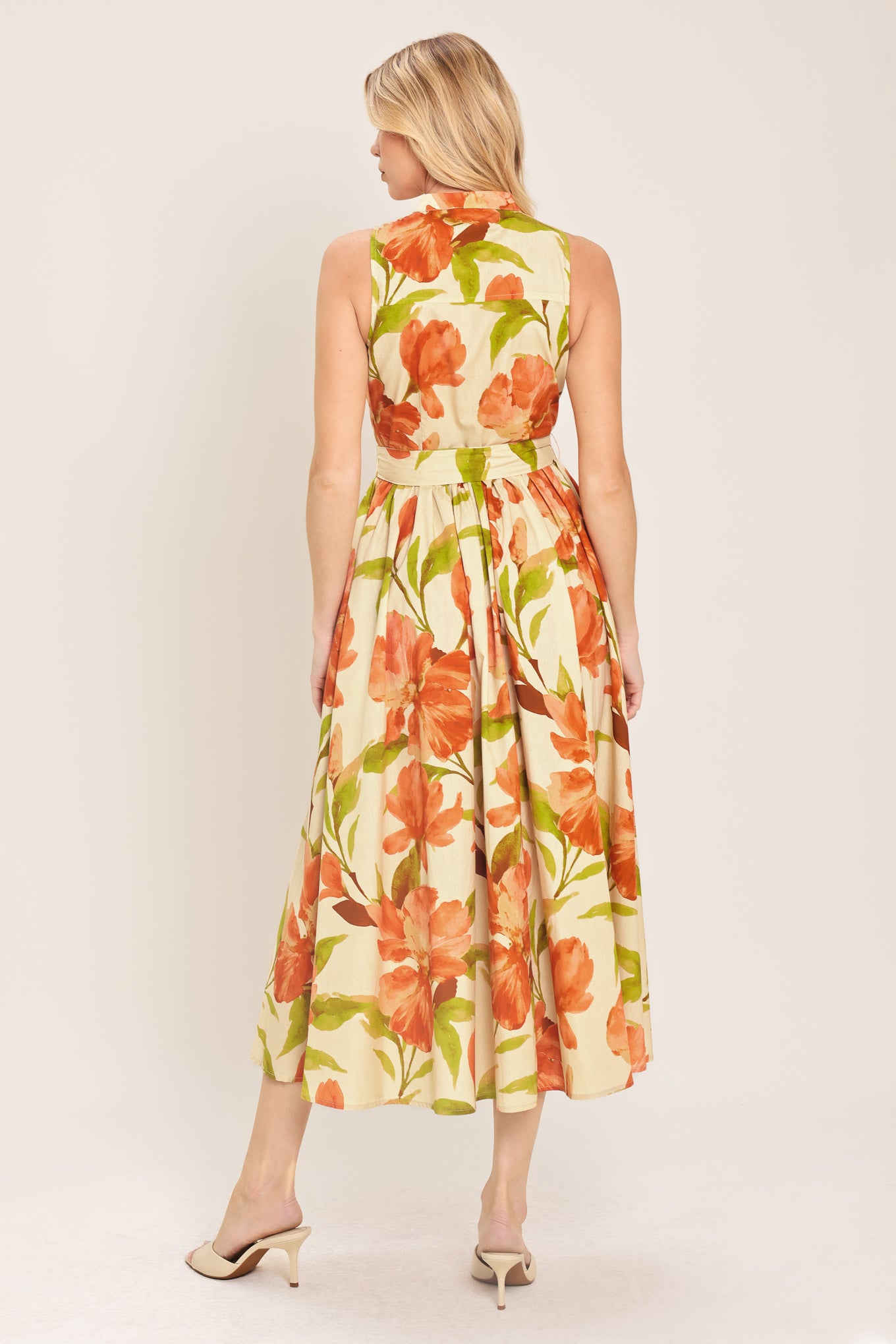 Woman wearing a sleeveless ivory and apricot floral midi dress featuring band collar, button down, self sash tie and full skirt | Flying Tomato