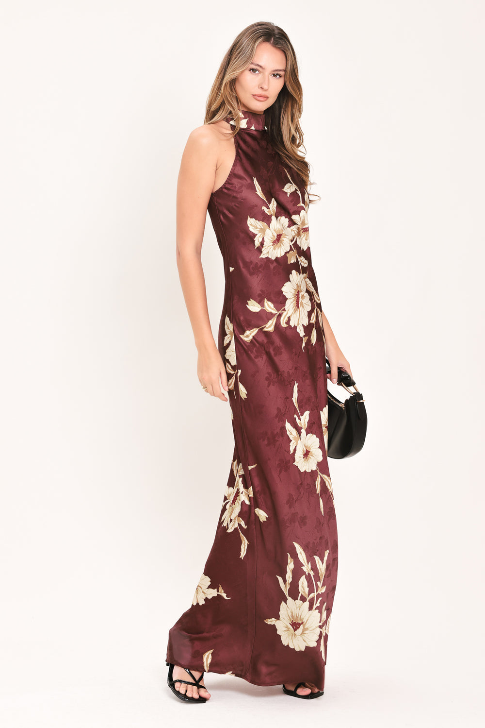 A woman modeling a sleeveless, high-neck floor-length maxi dress in deep burgundy with a cream floral print | FREEMARKET