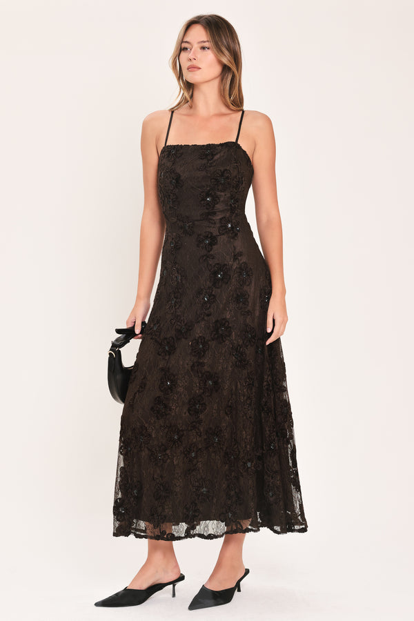 A woman modeling a brown lace midi dress with thin spaghetti straps, a fitted bodice, and a flared skirt | Flying Tomato