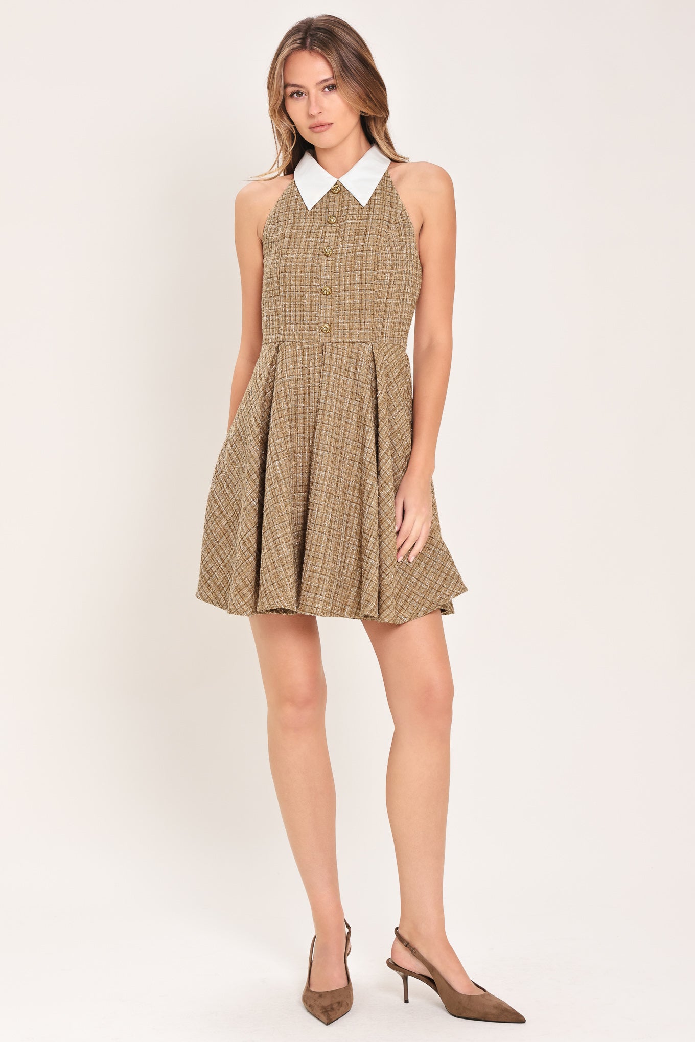 Woman wearing a hazel tweed mini dress featuring halter neckline with white collar finish, front button detail, full circle skirt and back zipper closure background | Flying Tomato