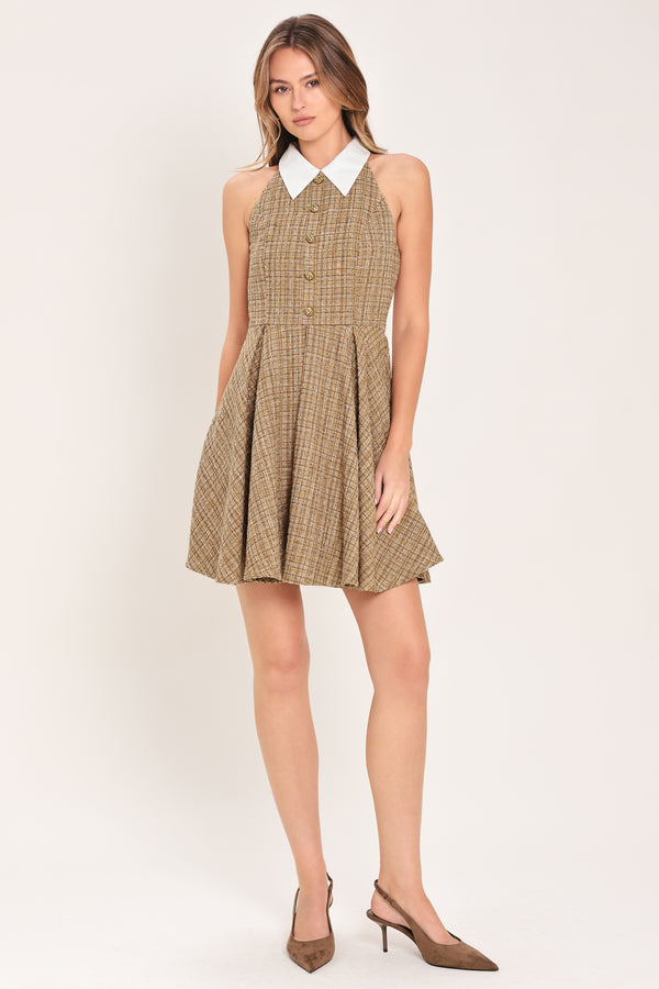 Woman wearing a hazel tweed mini dress featuring halter neckline with white collar finish, front button detail, full circle skirt and back zipper closure background | Flying Tomato